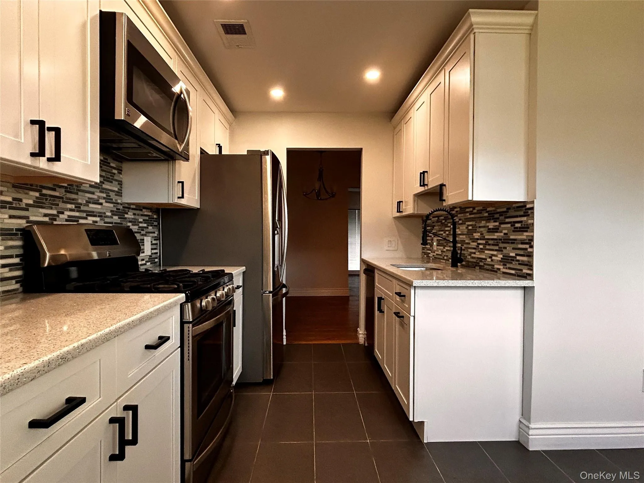 Kitchen with appliances with stainless steel finishes, decorative backsplash, white cabinets, and recessed lighting Kitchen with appliances with stainless steel finishes, decorative backsplash, white cabinets, and recessed lighting