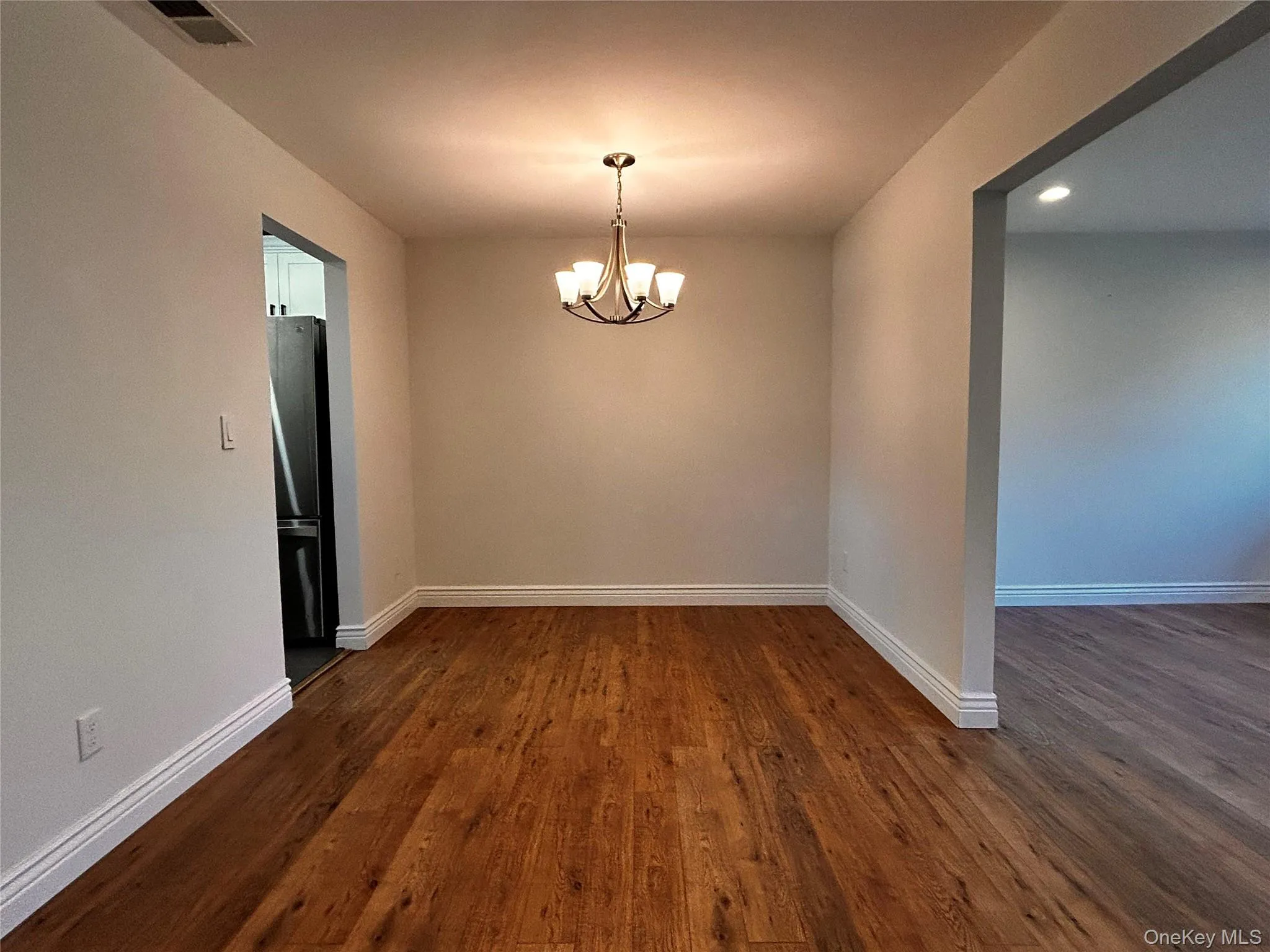 Spare room featuring dark wood-style flooring, a chandelier, and recessed lighting Spare room featuring dark wood-style flooring, a chandelier, and recessed lighting