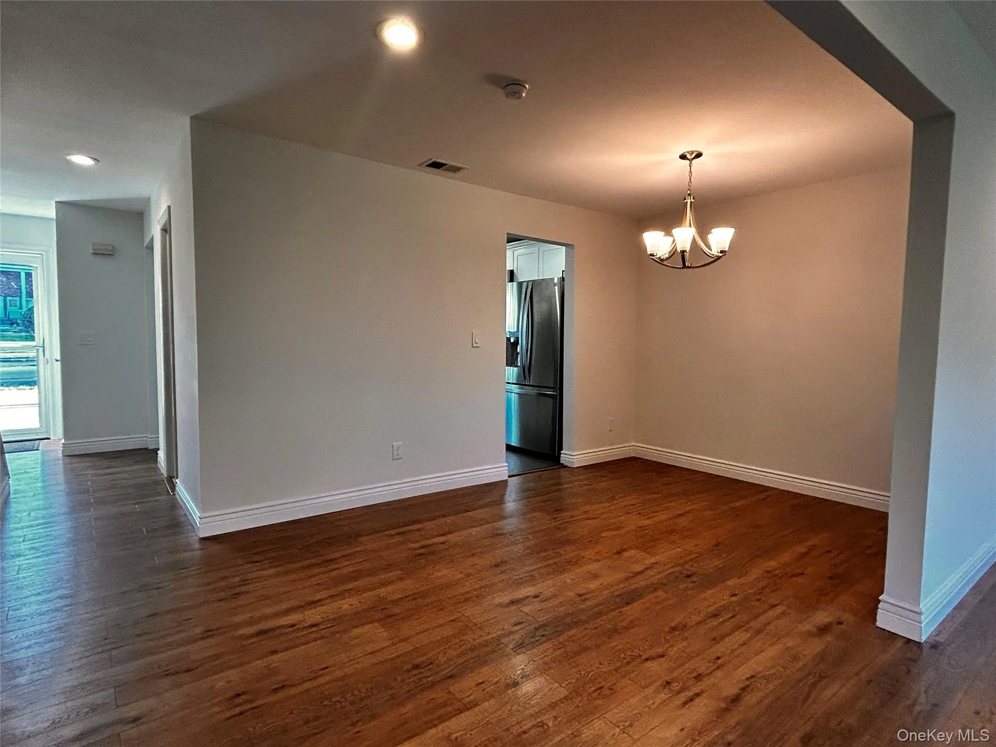 Unfurnished room featuring dark wood-style floors, a chandelier, and recessed lighting Unfurnished room featuring dark wood-style floors, a chandelier, and recessed lighting