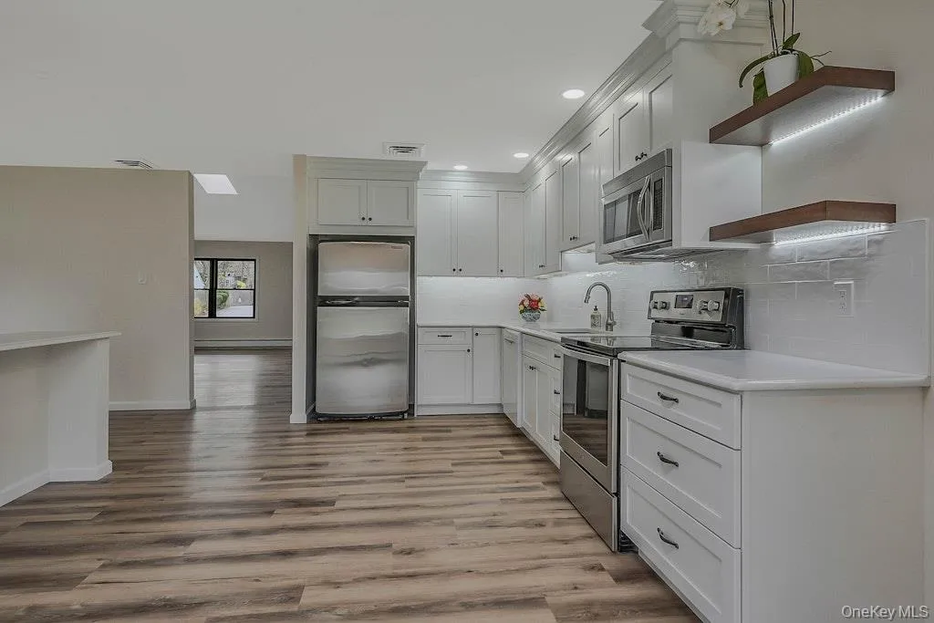 Kitchen with stainless steel appliances, tasteful backsplash, light wood finished floors, recessed lighting, and white cabinets Kitchen with stainless steel appliances, tasteful backsplash, light wood finished floors, recessed lighting, and white cabinets