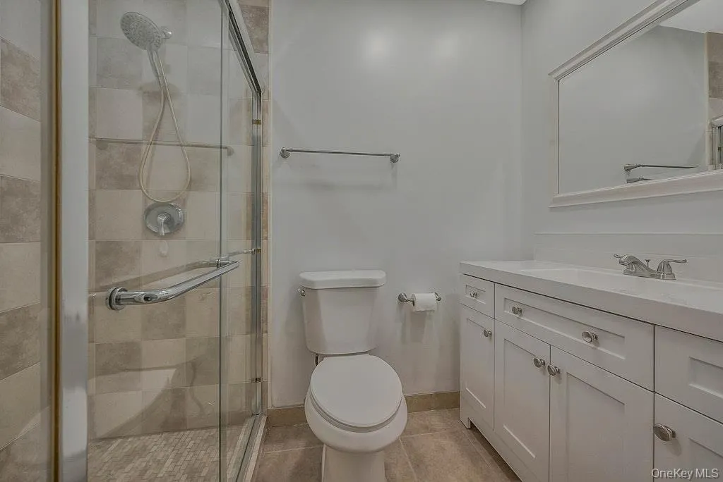 Bathroom featuring vanity, a shower stall, and light tile patterned floors Bathroom featuring vanity, a shower stall, and light tile patterned floors