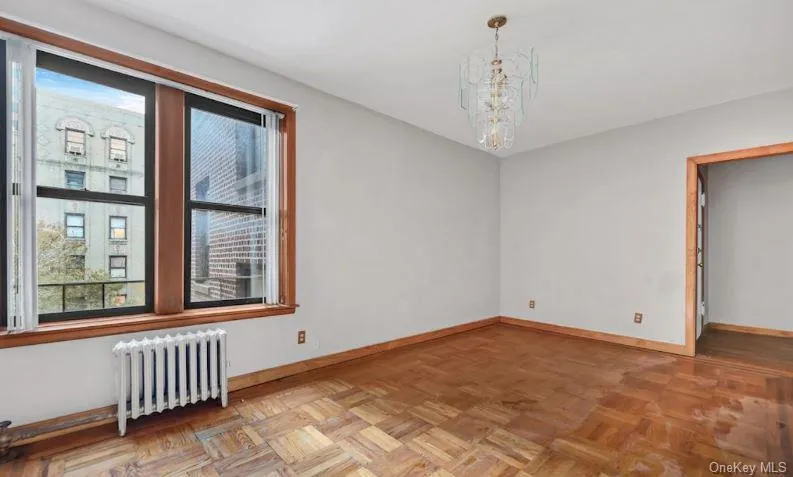 Empty room featuring radiator heating unit and a chandelier Empty room featuring radiator heating unit and a chandelier