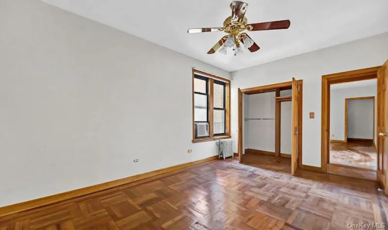Unfurnished bedroom featuring a ceiling fan, a closet, and radiator heating unit Unfurnished bedroom featuring a ceiling fan, a closet, and radiator heating unit