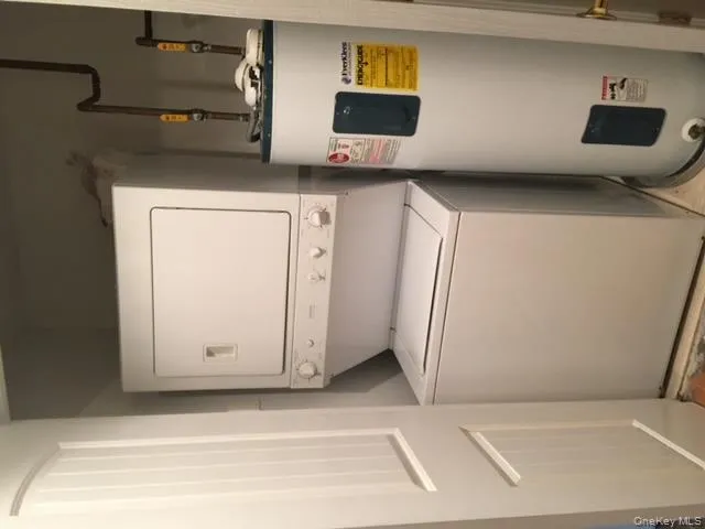 Laundry room featuring water heater and estacked washer and dryer Laundry room featuring water heater and estacked washer and dryer