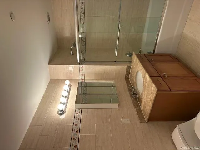 Bathroom featuring tile walls, enclosed tub / shower combo, vanity, and light tile patterned flooring Bathroom featuring tile walls, enclosed tub / shower combo, vanity, and light tile patterned flooring
