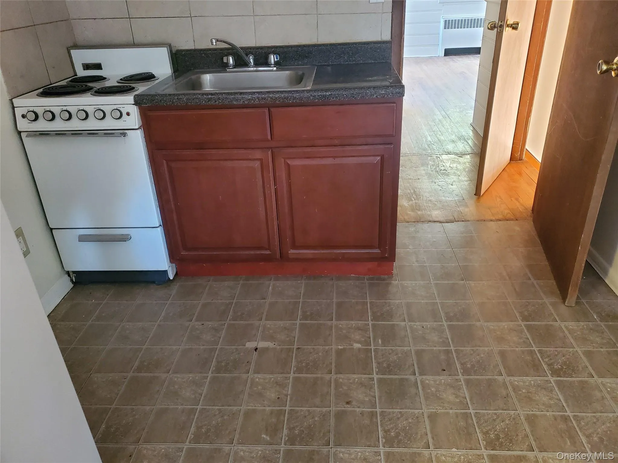 Kitchen featuring electric range, dark countertops, and radiator Kitchen featuring electric range, dark countertops, and radiator