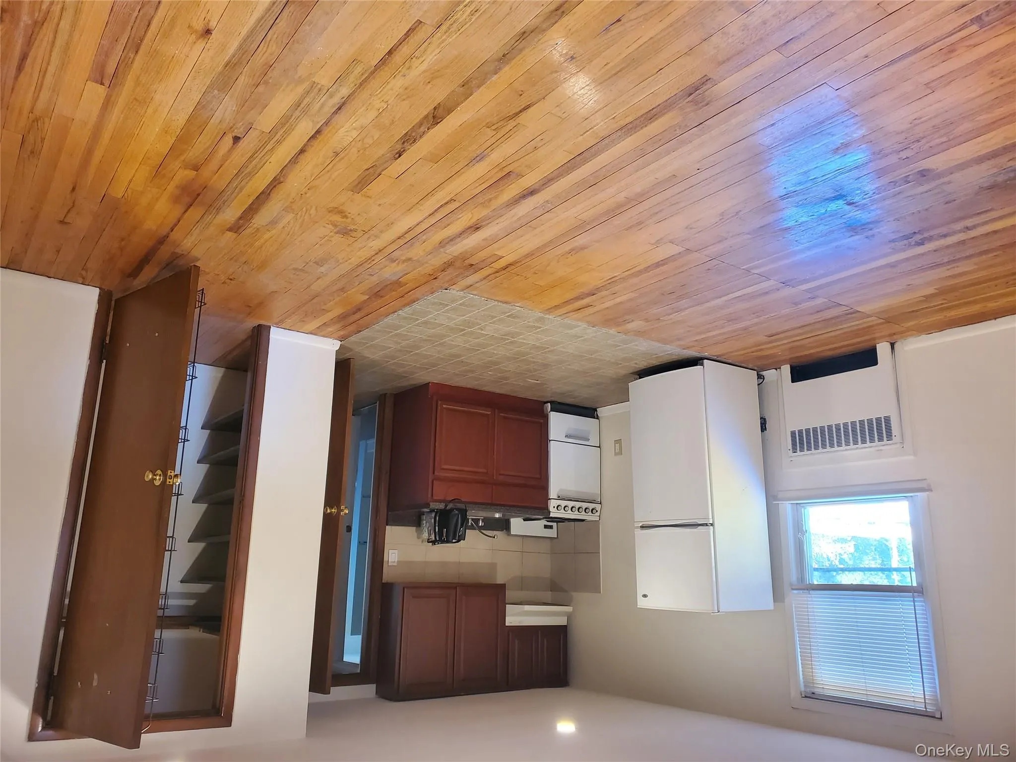 Kitchen with dark countertops, refrigerator, range, radiator heating unit, and light wood finished floors Kitchen with dark countertops, refrigerator, range, radiator heating unit, and light wood finished floors