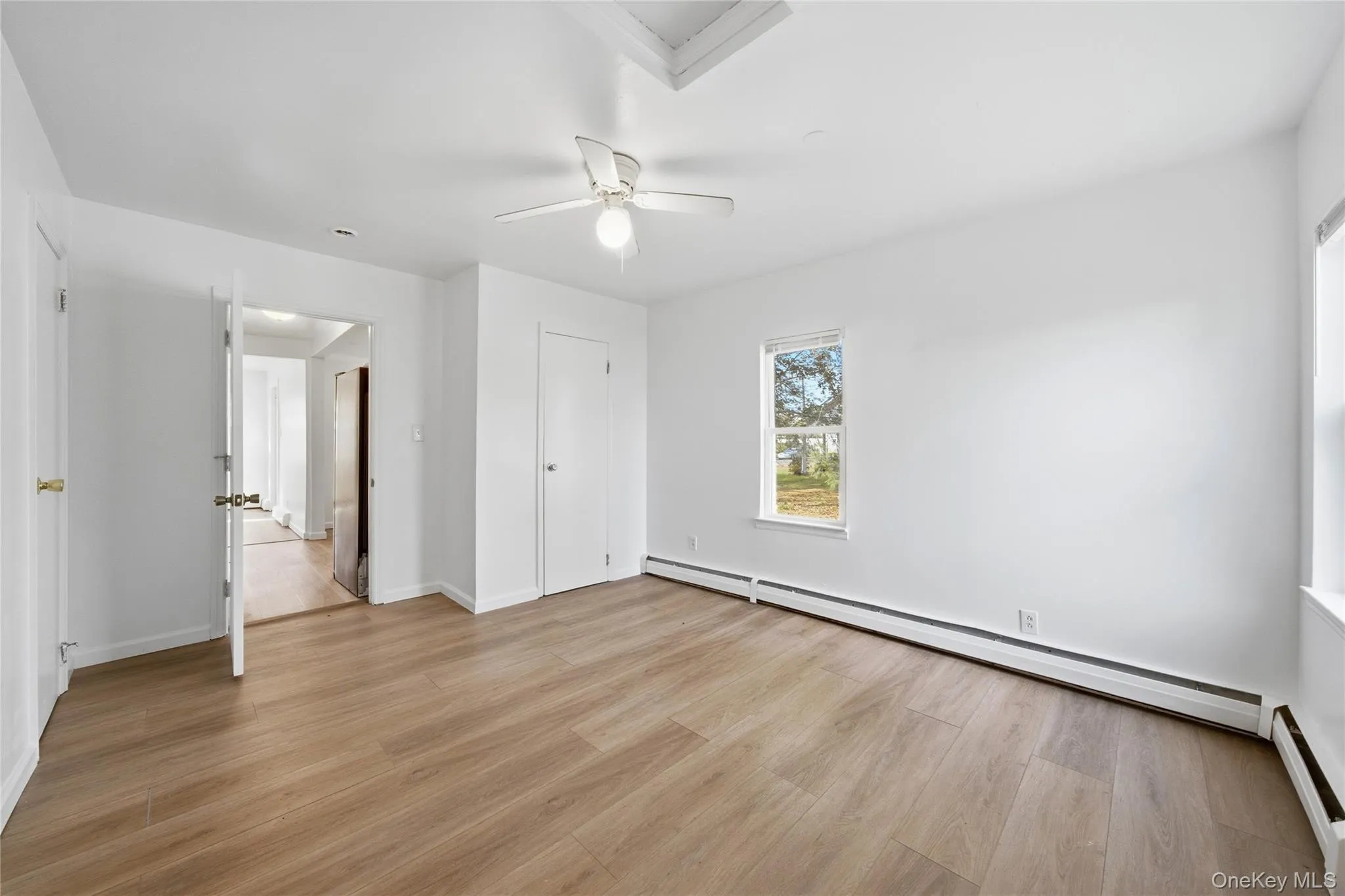 Unfurnished bedroom with light wood-style floors, a baseboard heating unit, and ceiling fan Unfurnished bedroom with light wood-style floors, a baseboard heating unit, and ceiling fan