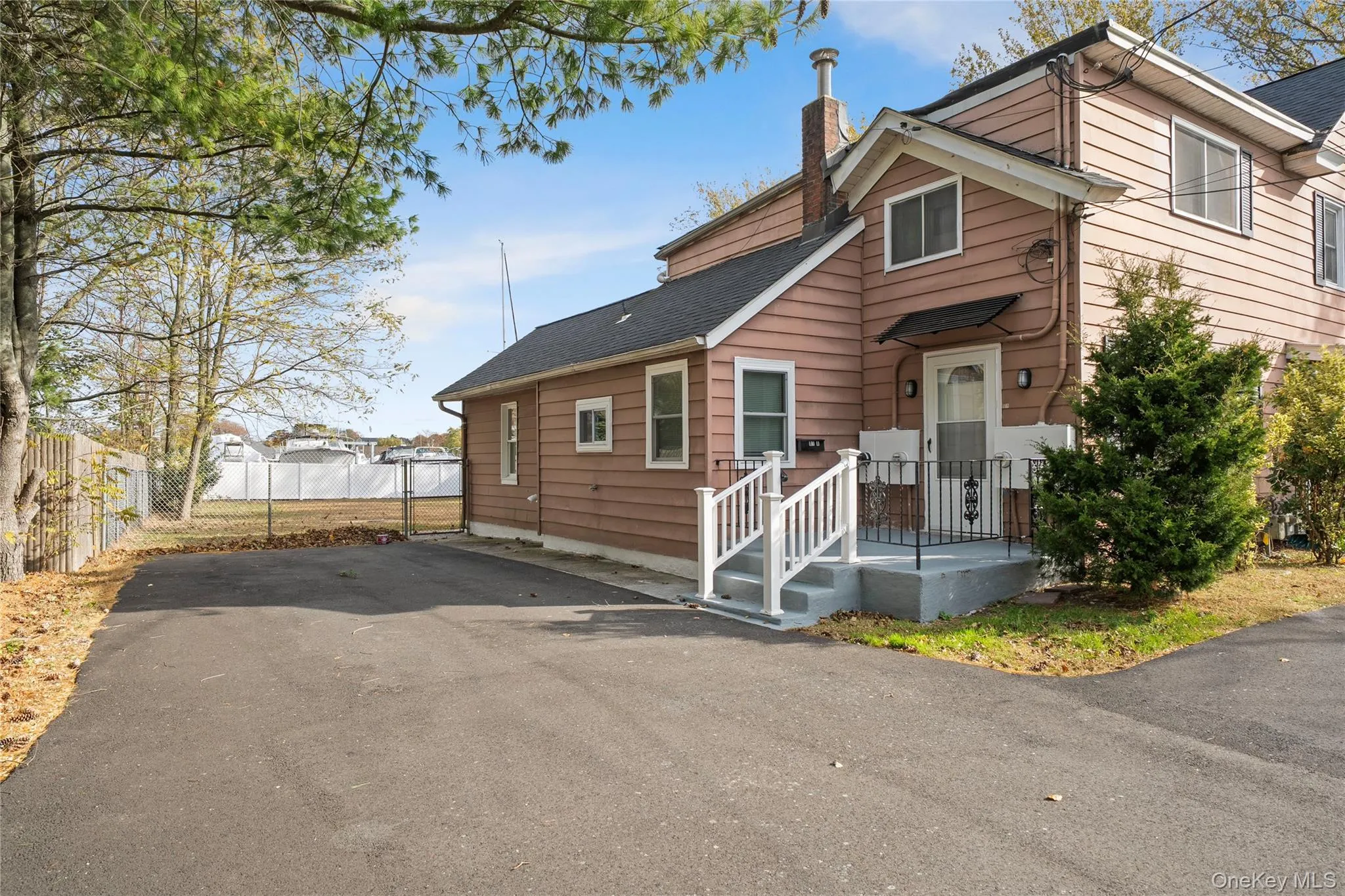 View of front of property featuring a chimney, a shingled roof, and asphalt driveway View of front of property featuring a chimney, a shingled roof, and asphalt driveway