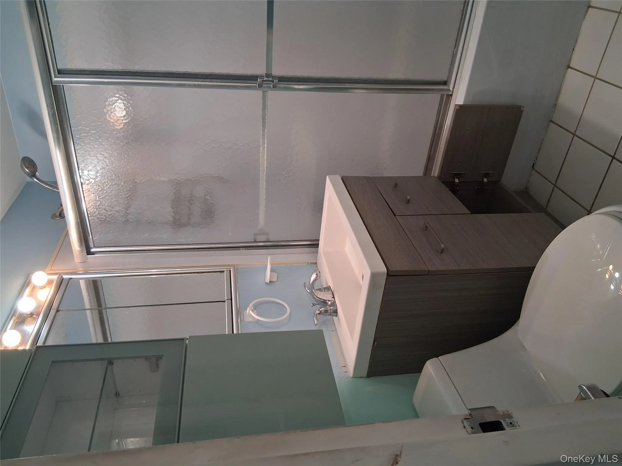 Bathroom with light tile patterned floors, vanity, and shower / bath combination with glass door Bathroom with light tile patterned floors, vanity, and shower / bath combination with glass door