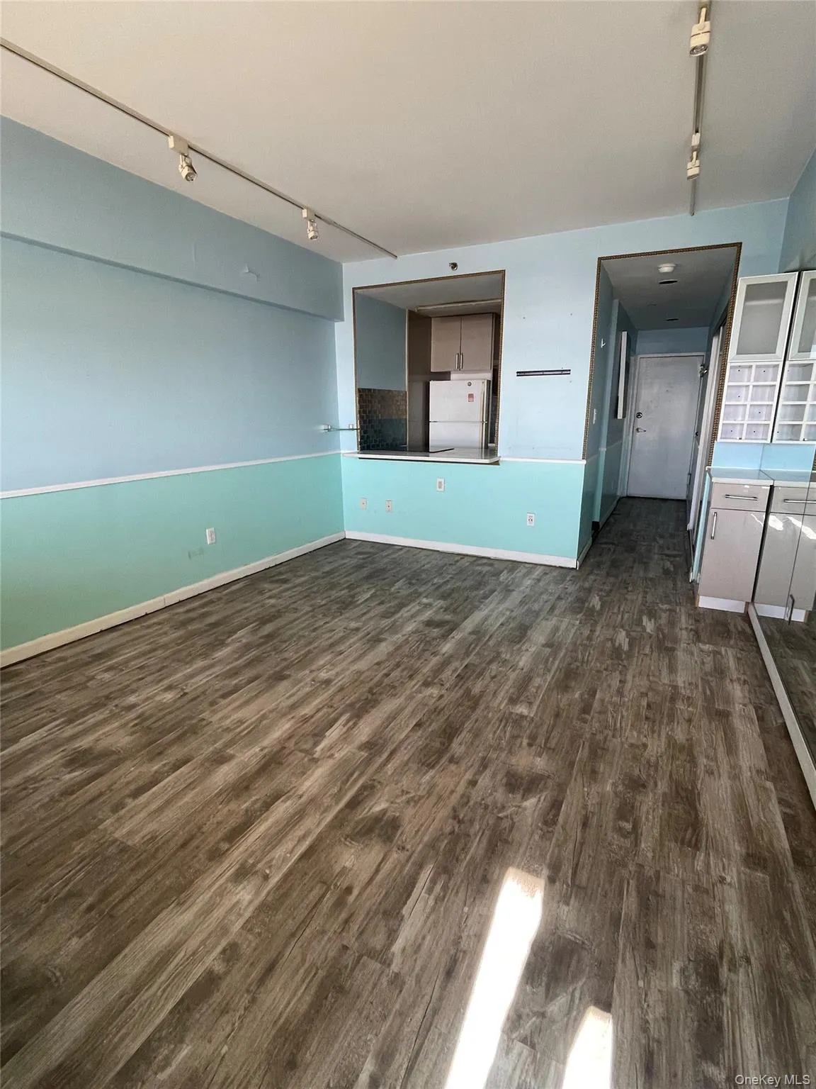 Unfurnished living room with rail lighting and dark wood finished floors Unfurnished living room with rail lighting and dark wood finished floors