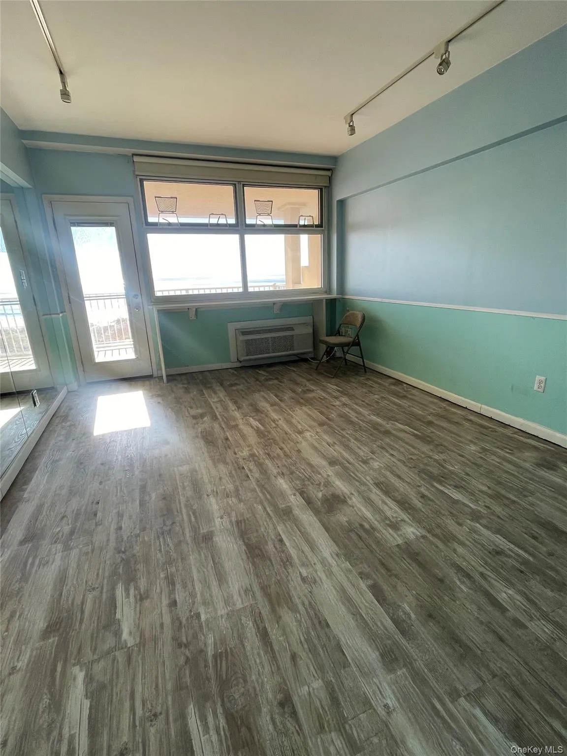 Unfurnished room featuring track lighting and dark wood finished floors Unfurnished room featuring track lighting and dark wood finished floors