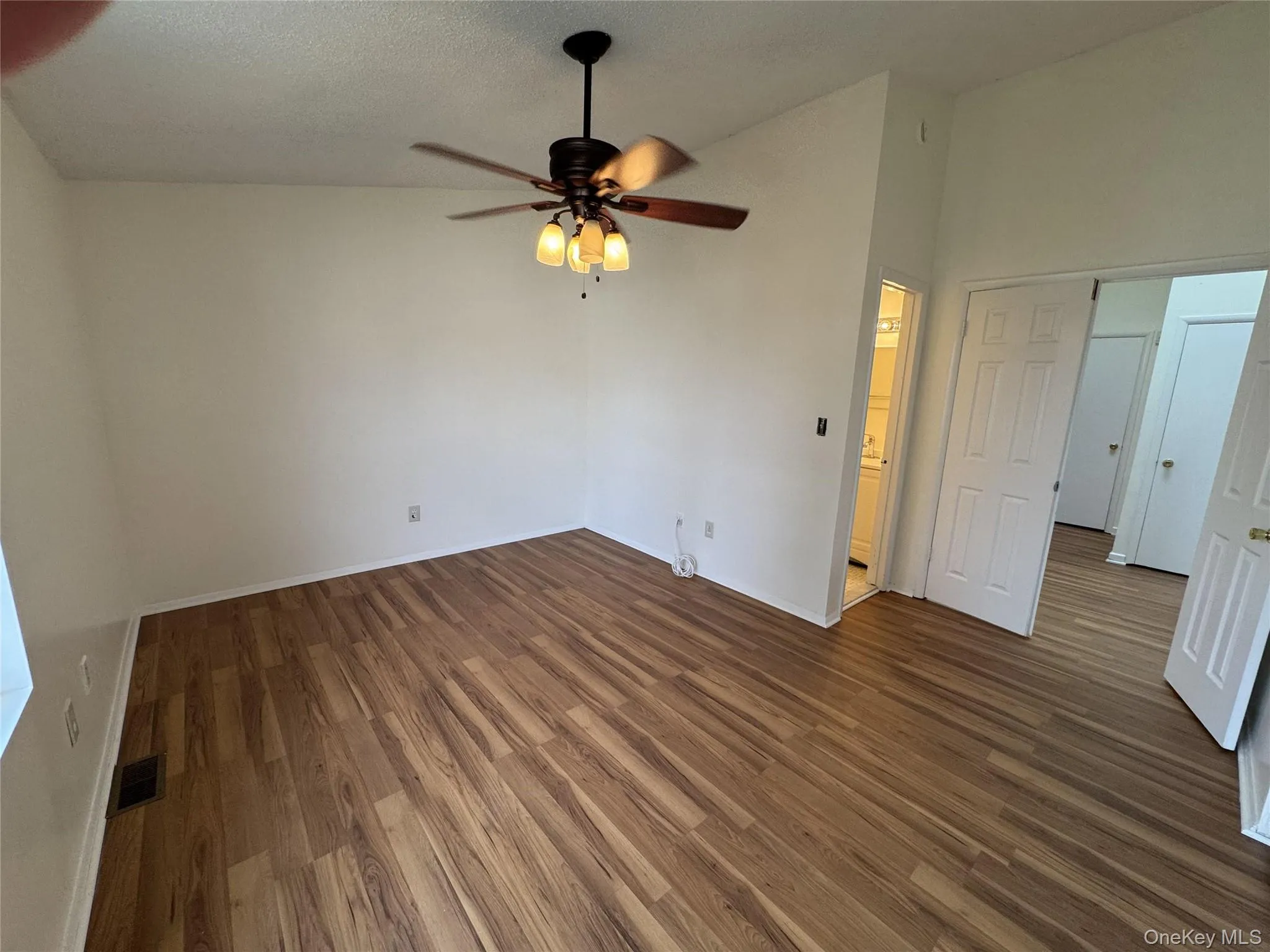 Unfurnished bedroom with dark wood finished floors, ceiling fan, and a textured ceiling Unfurnished bedroom with dark wood finished floors, ceiling fan, and a textured ceiling