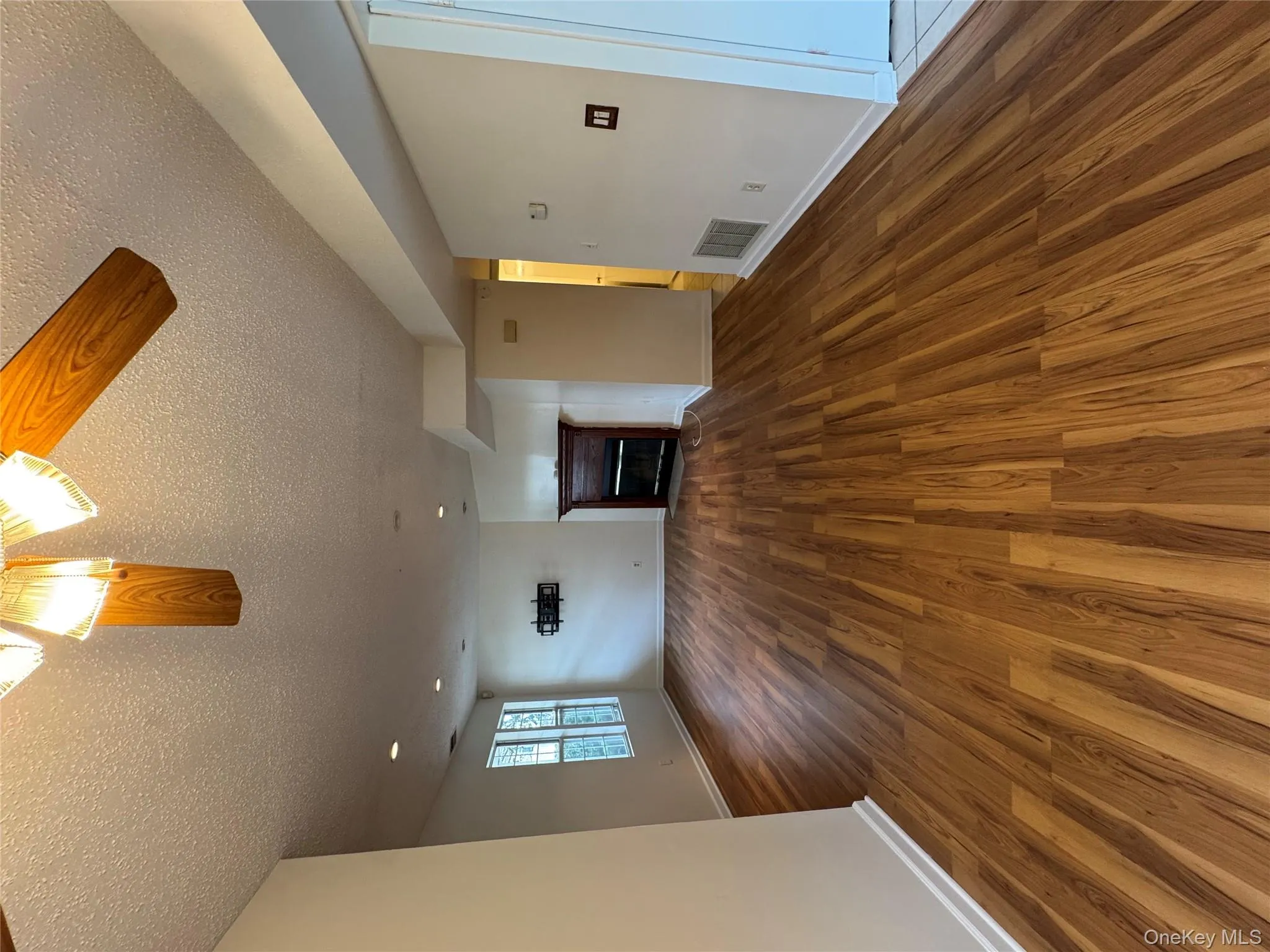 Unfurnished living room featuring a fireplace, dark wood-style floors, a textured ceiling, and a ceiling fan Unfurnished living room featuring a fireplace, dark wood-style floors, a textured ceiling, and a ceiling fan