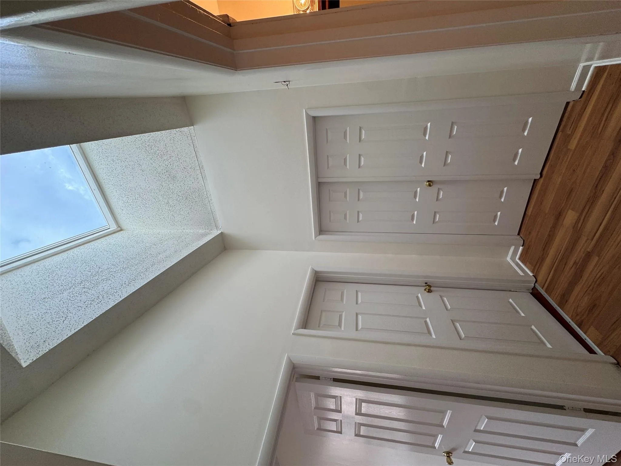 Hallway featuring a skylight and dark wood-type flooring Hallway featuring a skylight and dark wood-type flooring