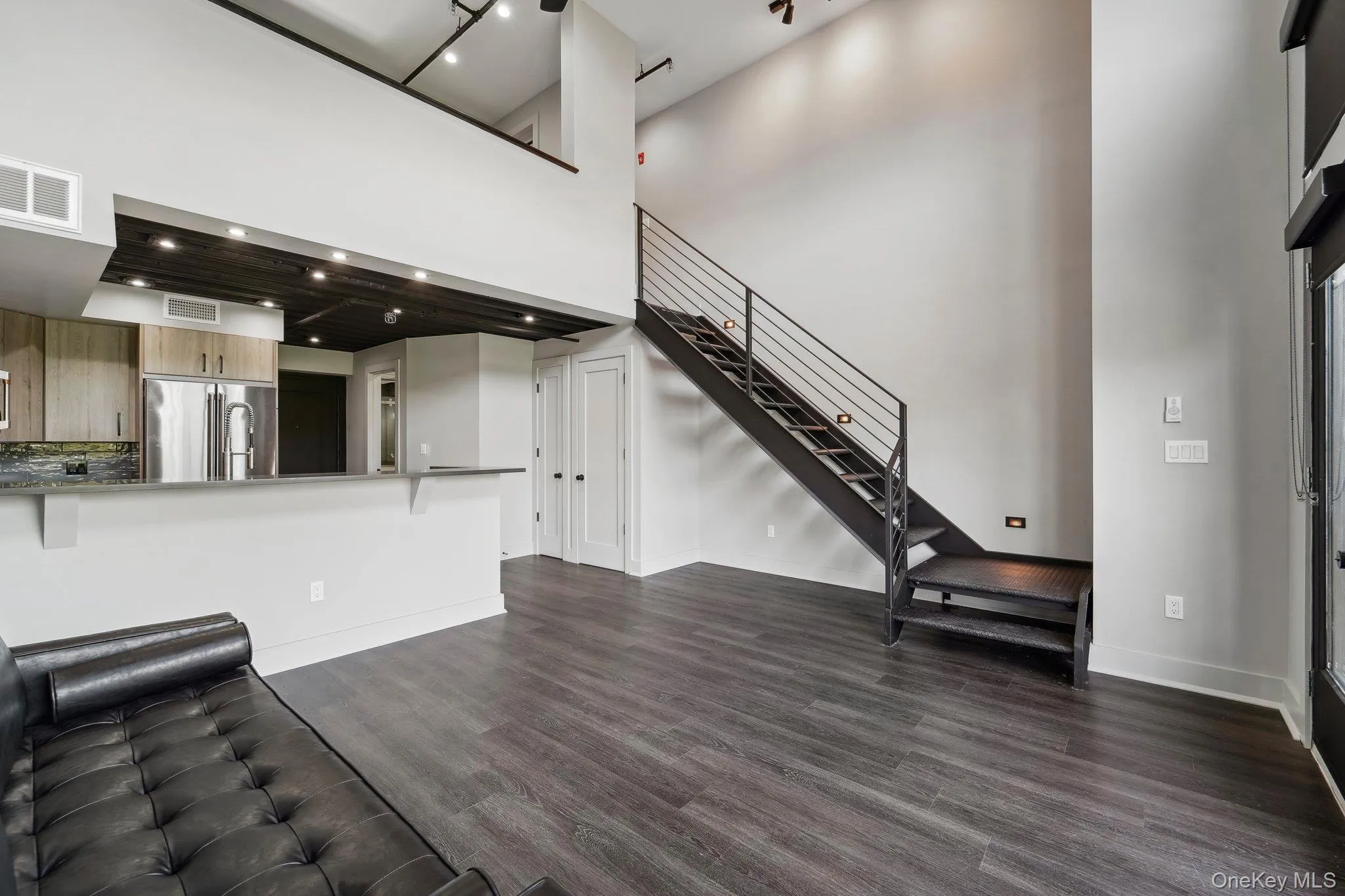 Unfurnished living room featuring a high ceiling, dark wood-style flooring, and stairs Unfurnished living room featuring a high ceiling, dark wood-style flooring, and stairs