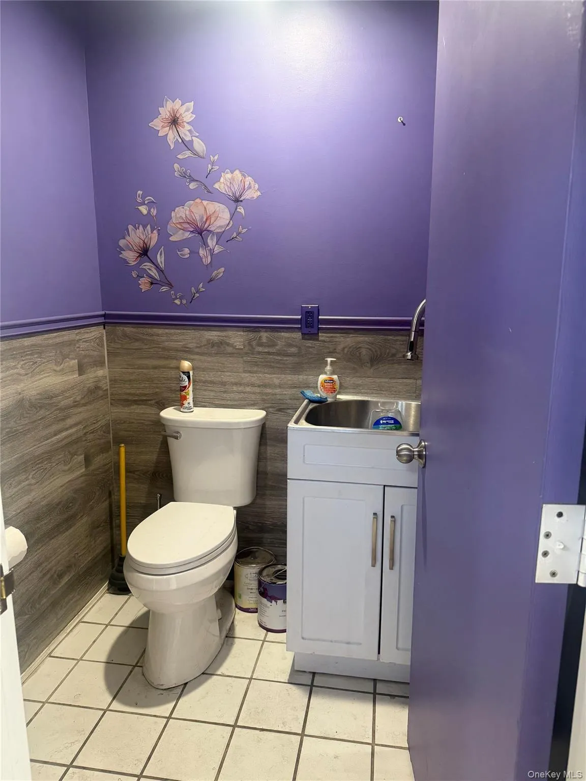 Half bath featuring vanity, light tile patterned flooring, and a wainscoted wall Half bath featuring vanity, light tile patterned flooring, and a wainscoted wall