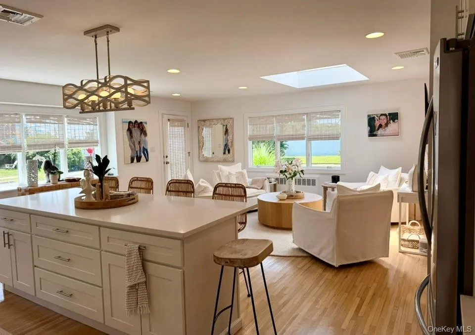 Kitchen featuring a breakfast bar, decorative light fixtures, freestanding refrigerator, white cabinetry, and light wood-style flooring Kitchen featuring a breakfast bar, decorative light fixtures, freestanding refrigerator, white cabinetry, and light wood-style flooring
