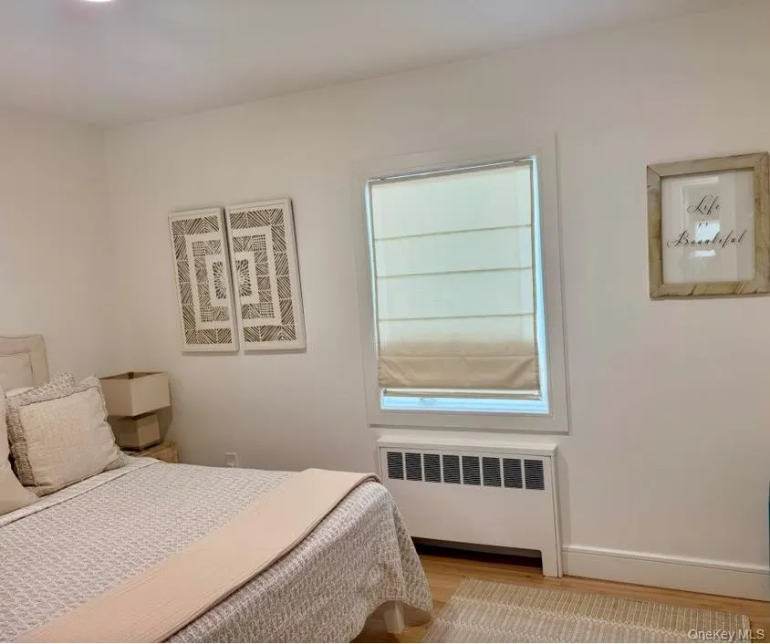 Bedroom featuring radiator and wood finished floors Bedroom featuring radiator and wood finished floors