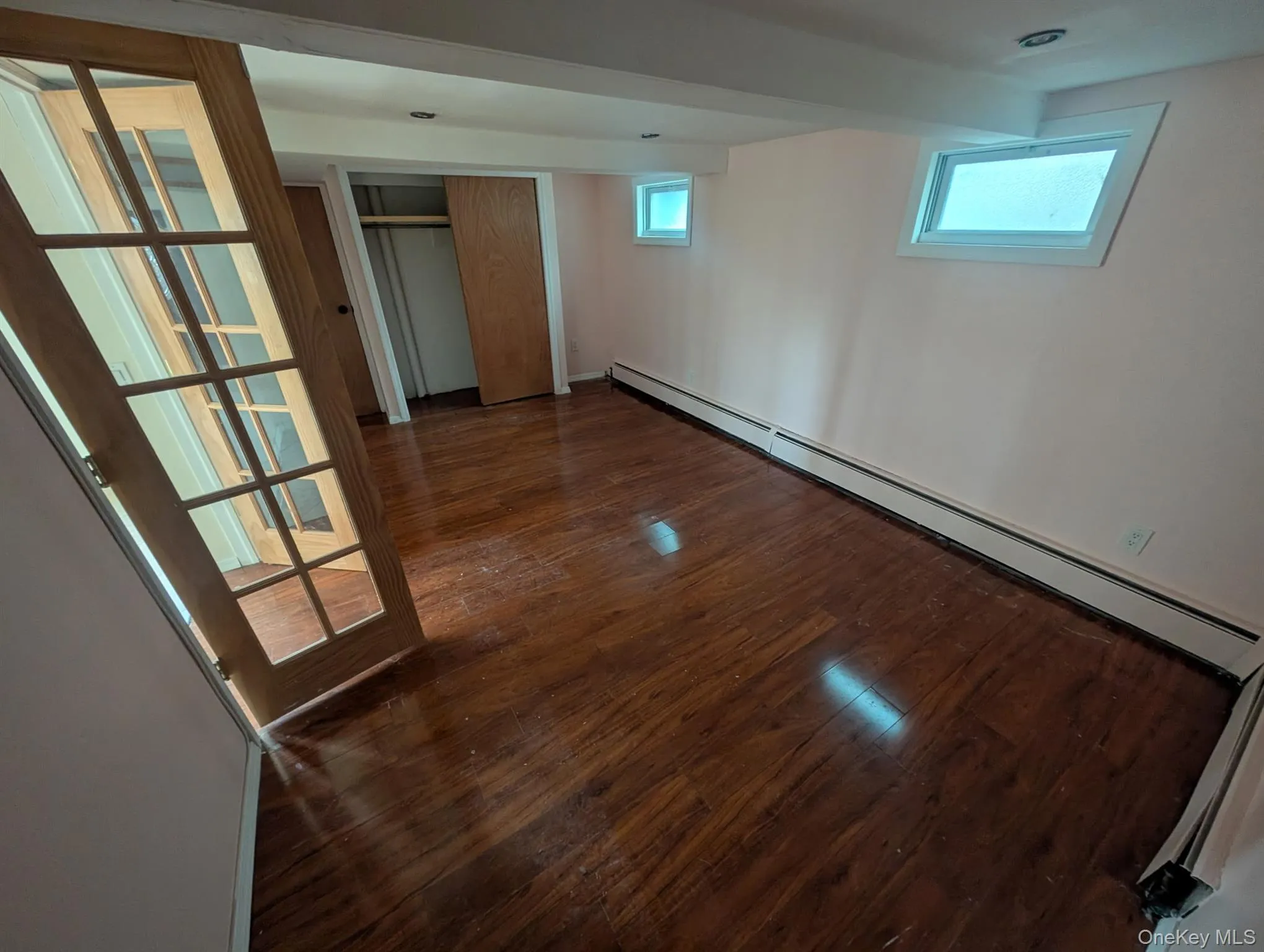 Below grade area with a baseboard heating unit, dark wood-type flooring, and healthy amount of natural light Below grade area with a baseboard heating unit, dark wood-type flooring, and healthy amount of natural light