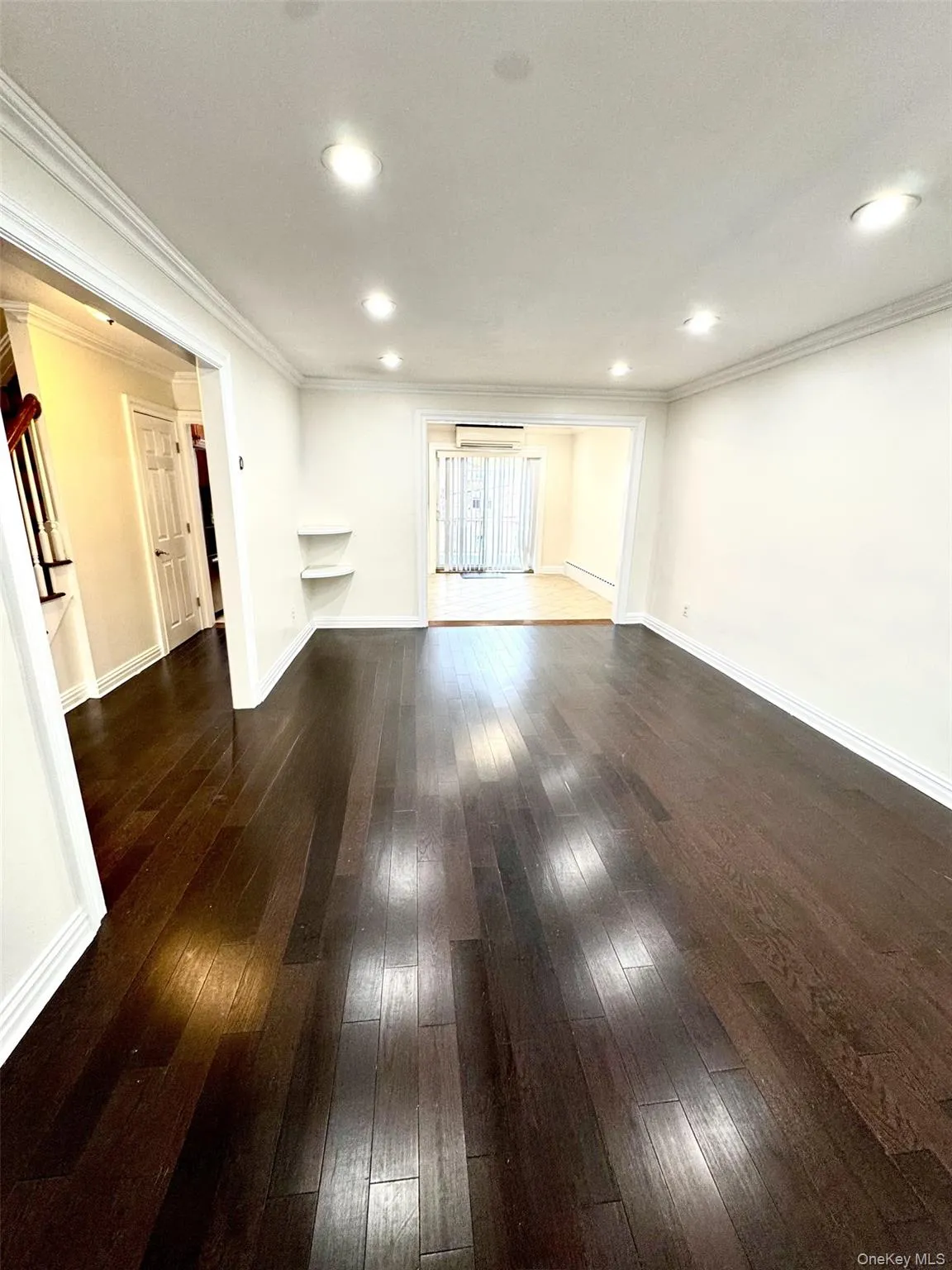 Unfurnished living room featuring ornamental molding, dark wood finished floors, recessed lighting, and a baseboard radiator Unfurnished living room featuring ornamental molding, dark wood finished floors, recessed lighting, and a baseboard radiator