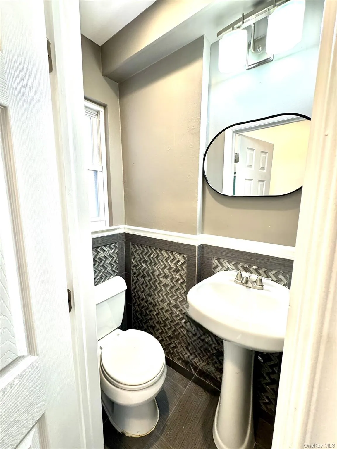 Half bathroom with wainscoting, tile walls, and tile patterned floors Half bathroom with wainscoting, tile walls, and tile patterned floors