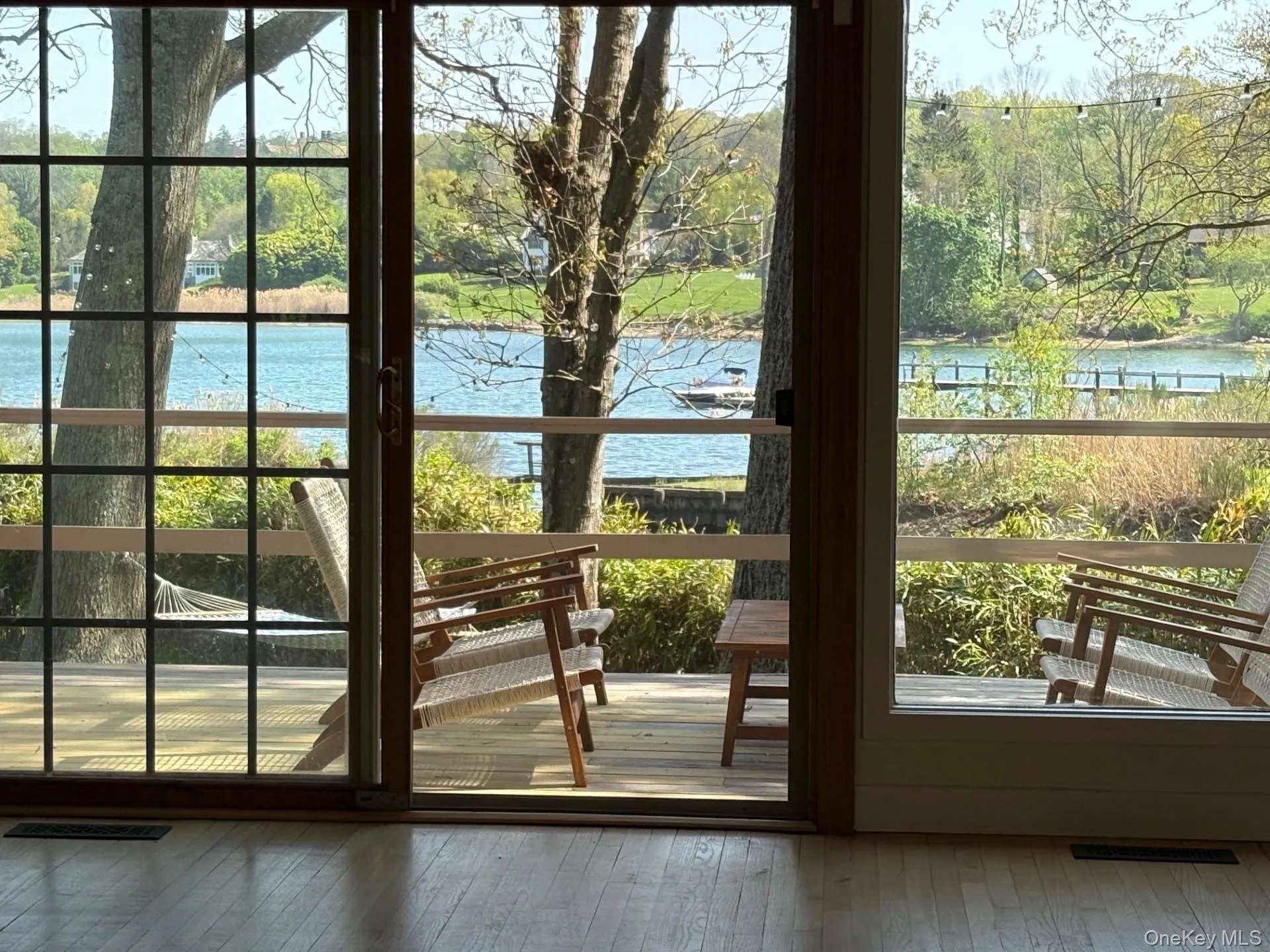 Sliding glass doors opening to an exterior deck with water and lush greenery beyond Sliding glass doors opening to an exterior deck with water and lush greenery beyond