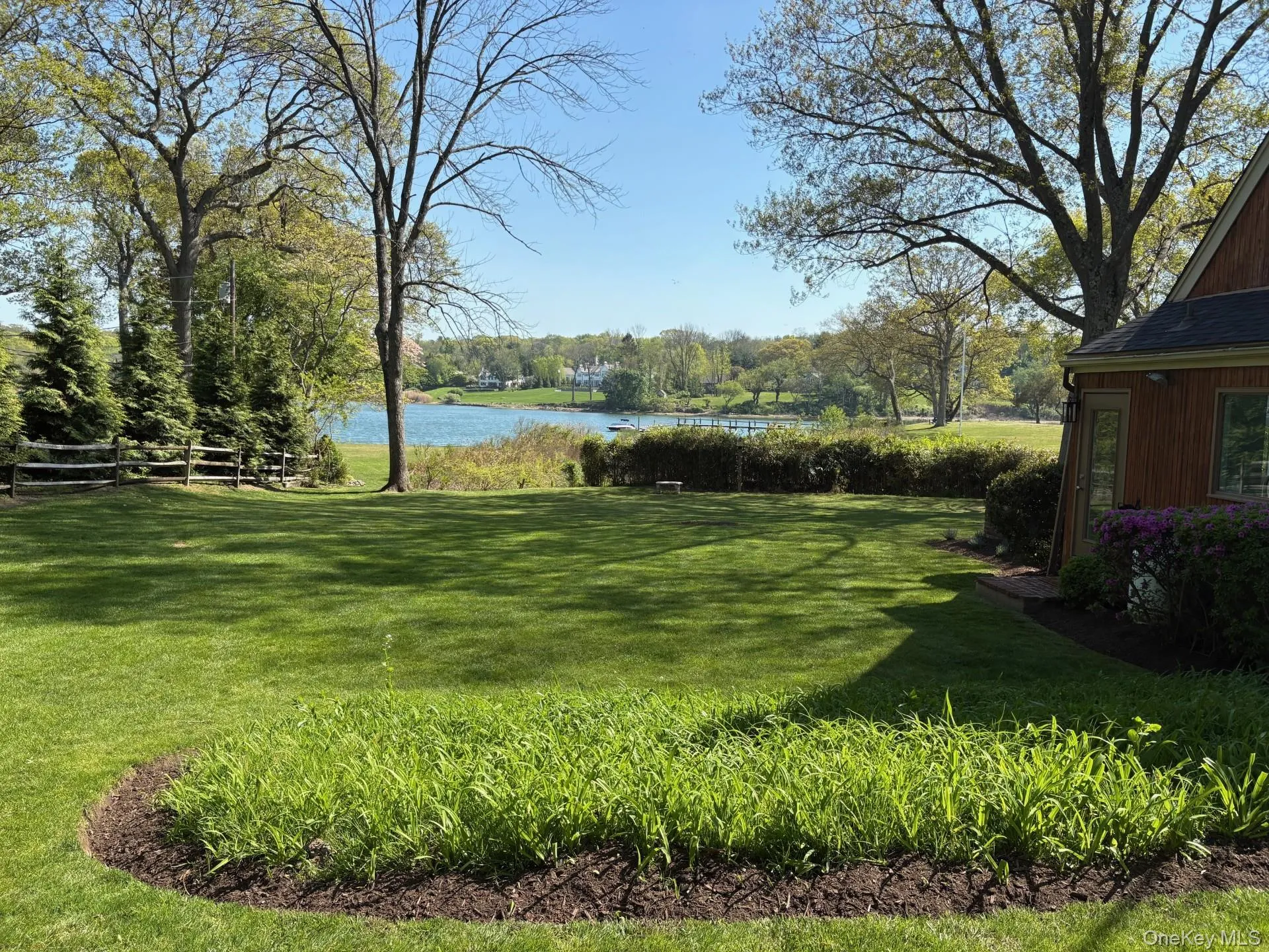 Expansive green lawn with established trees and waterfront access Expansive green lawn with established trees and waterfront access