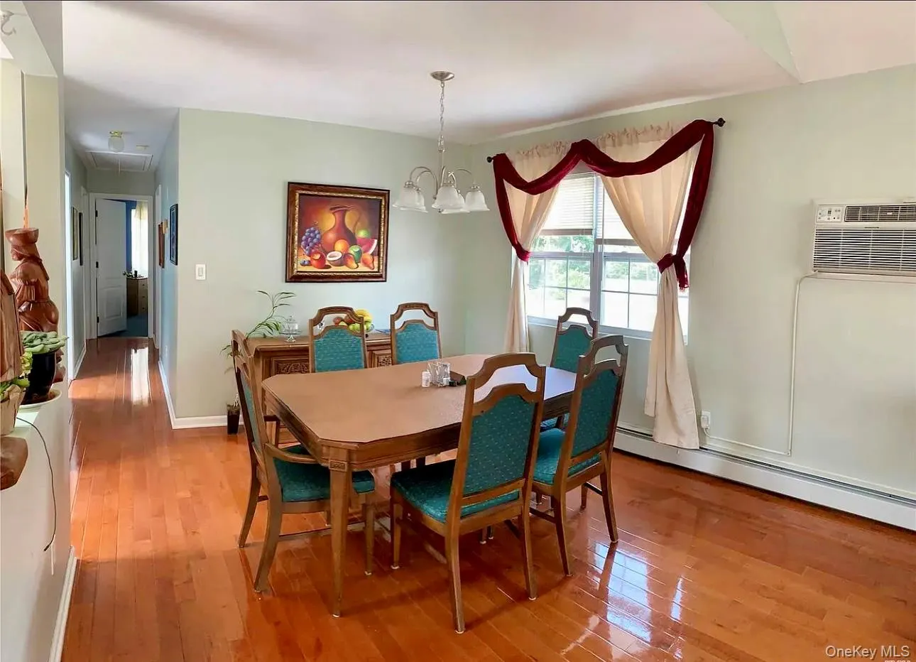 Dining room with hardwood / wood-style floors, a wall unit AC, a chandelier, attic access, and a baseboard heating unit Dining room with hardwood / wood-style floors, a wall unit AC, a chandelier, attic access, and a baseboard heating unit