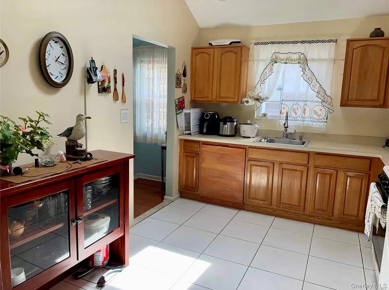 Kitchen featuring light countertops, brown cabinetry, light tile patterned flooring, and stove Kitchen featuring light countertops, brown cabinetry, light tile patterned flooring, and stove