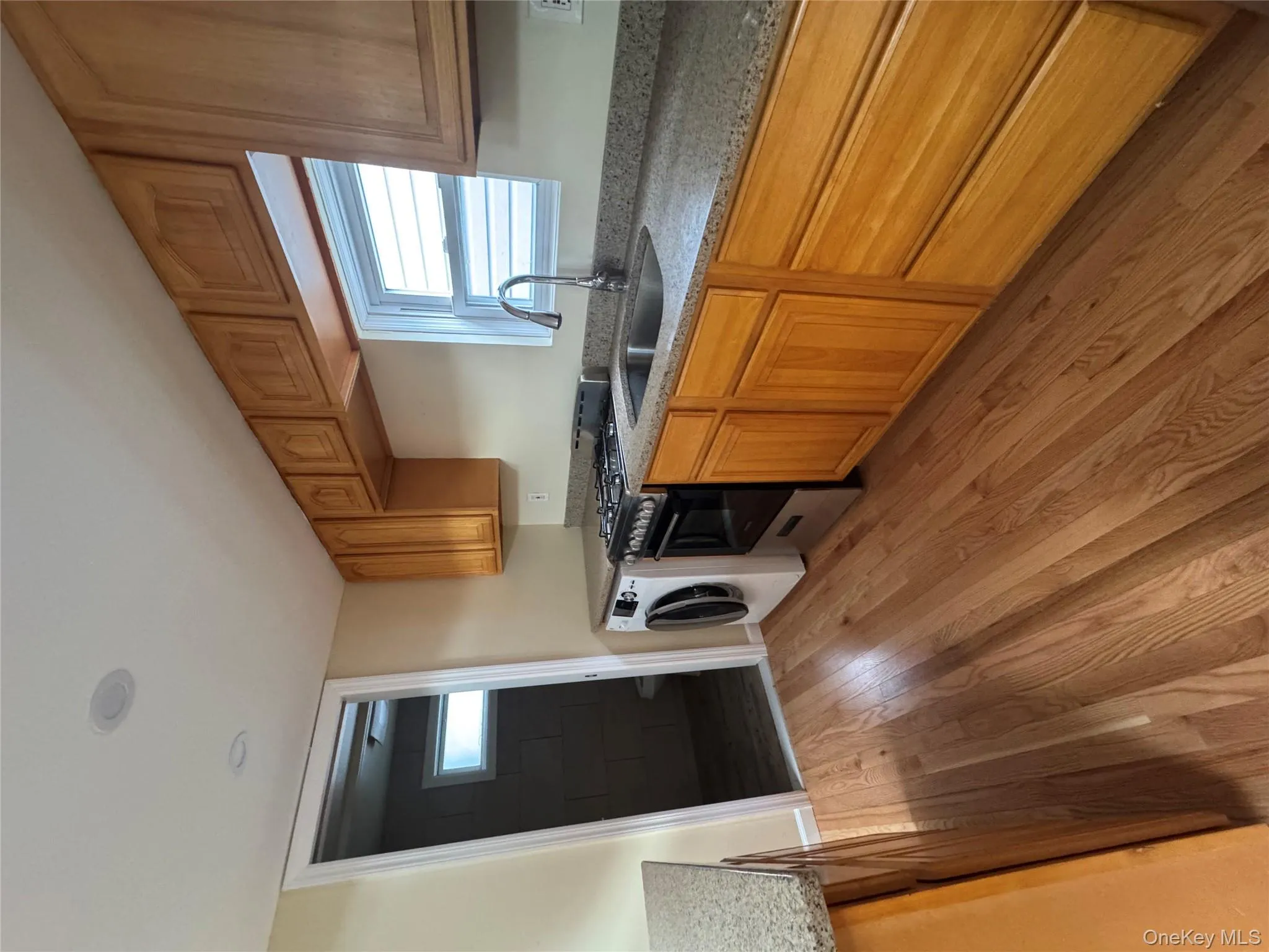 Kitchen with gas range, light stone countertops, brown cabinets, and light wood-style flooring Kitchen with gas range, light stone countertops, brown cabinets, and light wood-style flooring