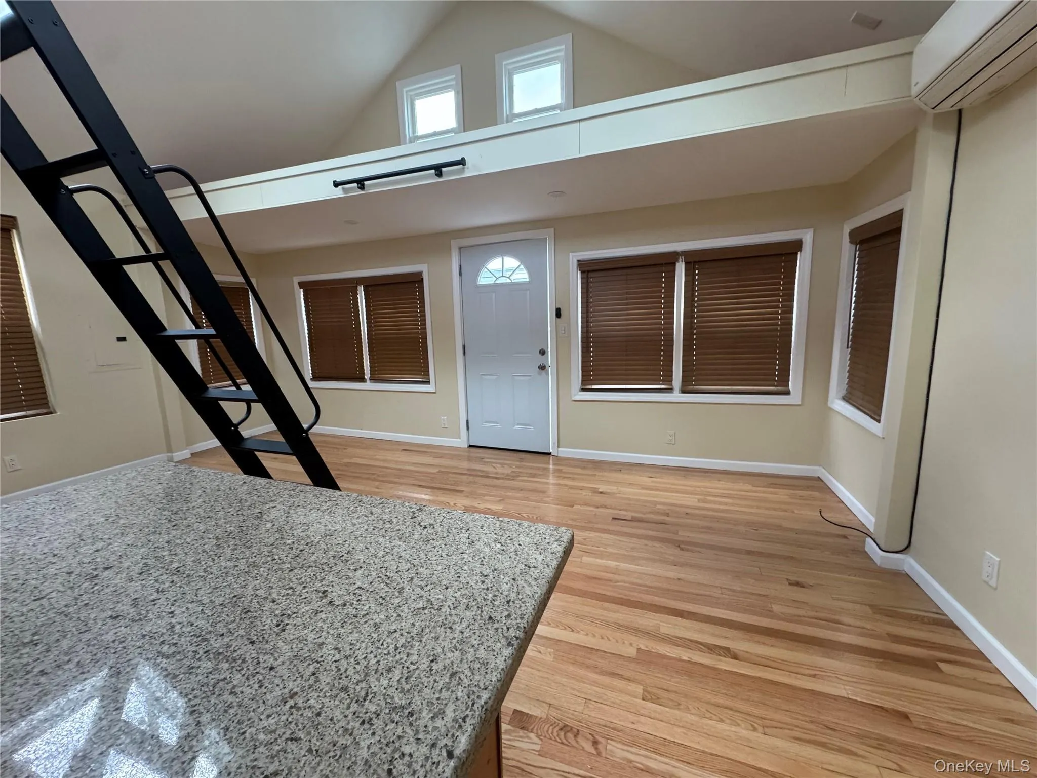 Entryway featuring high vaulted ceiling, a wall unit AC, and light wood-type flooring Entryway featuring high vaulted ceiling, a wall unit AC, and light wood-type flooring