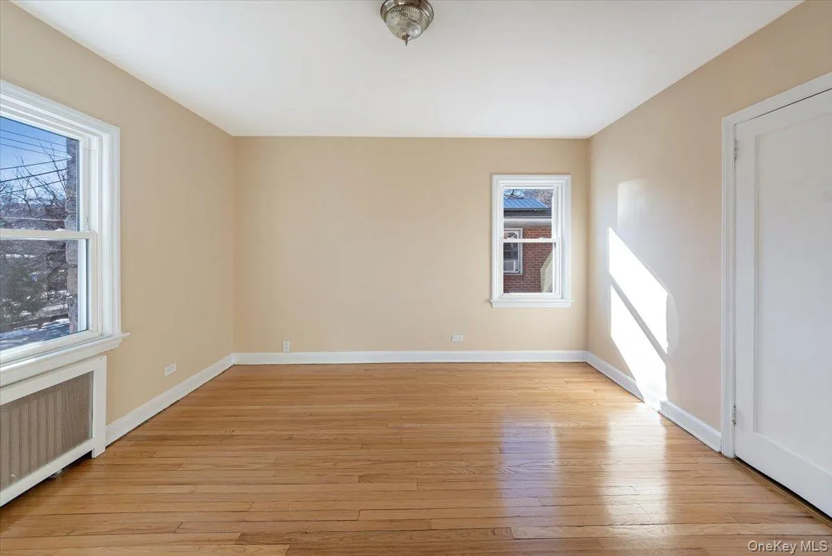 Empty room featuring light wood-type flooring, baseboards, and radiator heating unit Empty room featuring light wood-type flooring, baseboards, and radiator heating unit