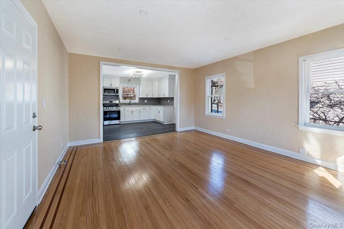 Unfurnished living room featuring a healthy amount of sunlight, baseboards, and wood finished floors Unfurnished living room featuring a healthy amount of sunlight, baseboards, and wood finished floors