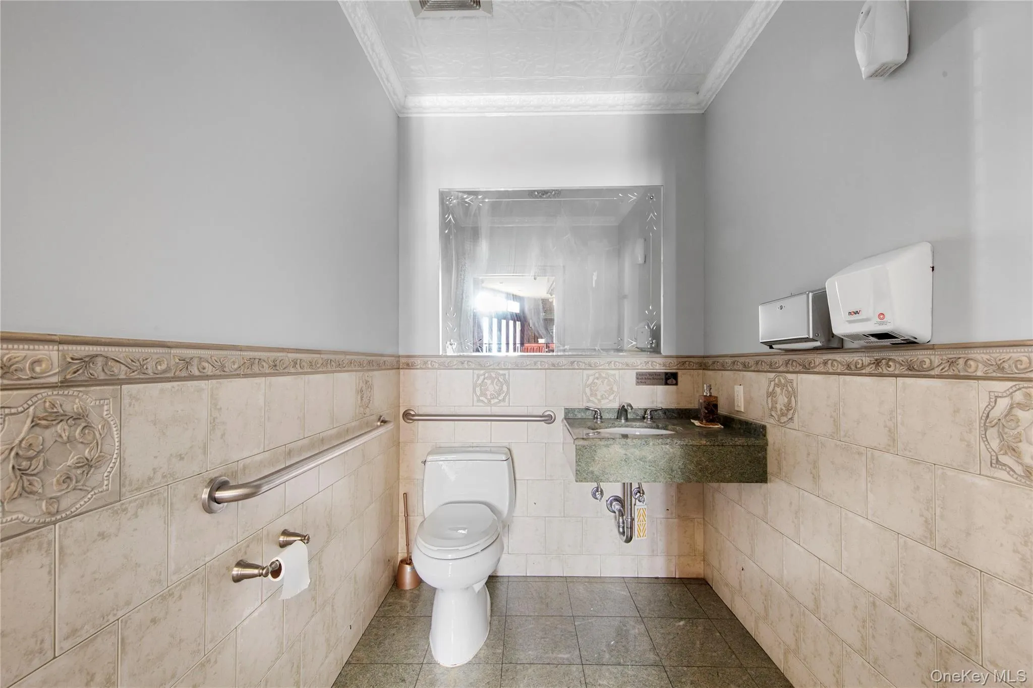 Half bathroom with tile walls, wainscoting, tile patterned floors, and an ornate ceiling Half bathroom with tile walls, wainscoting, tile patterned floors, and an ornate ceiling