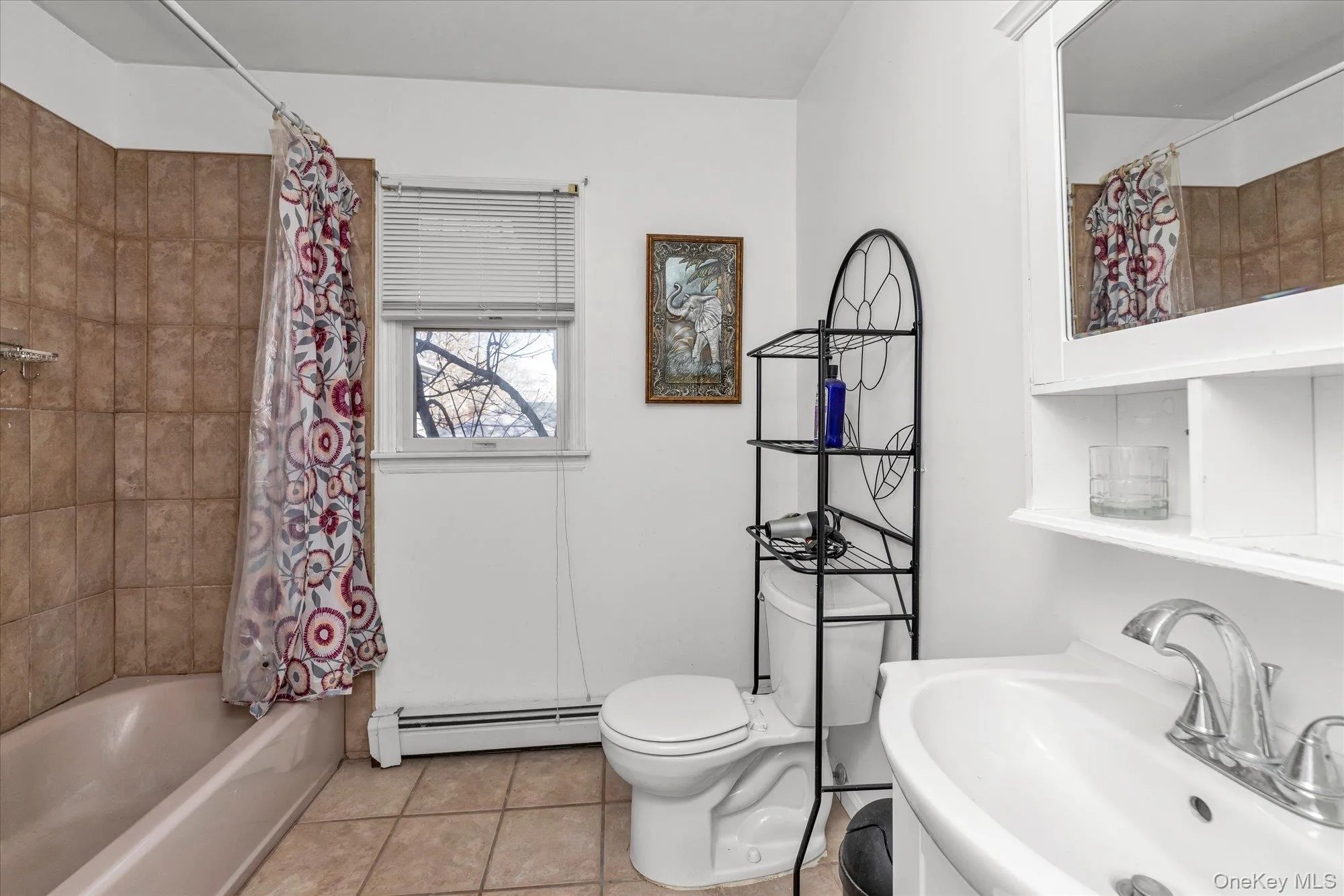 Full bathroom with shower / bath combo, light tile patterned flooring, a baseboard radiator, and vanity Full bathroom with shower / bath combo, light tile patterned flooring, a baseboard radiator, and vanity