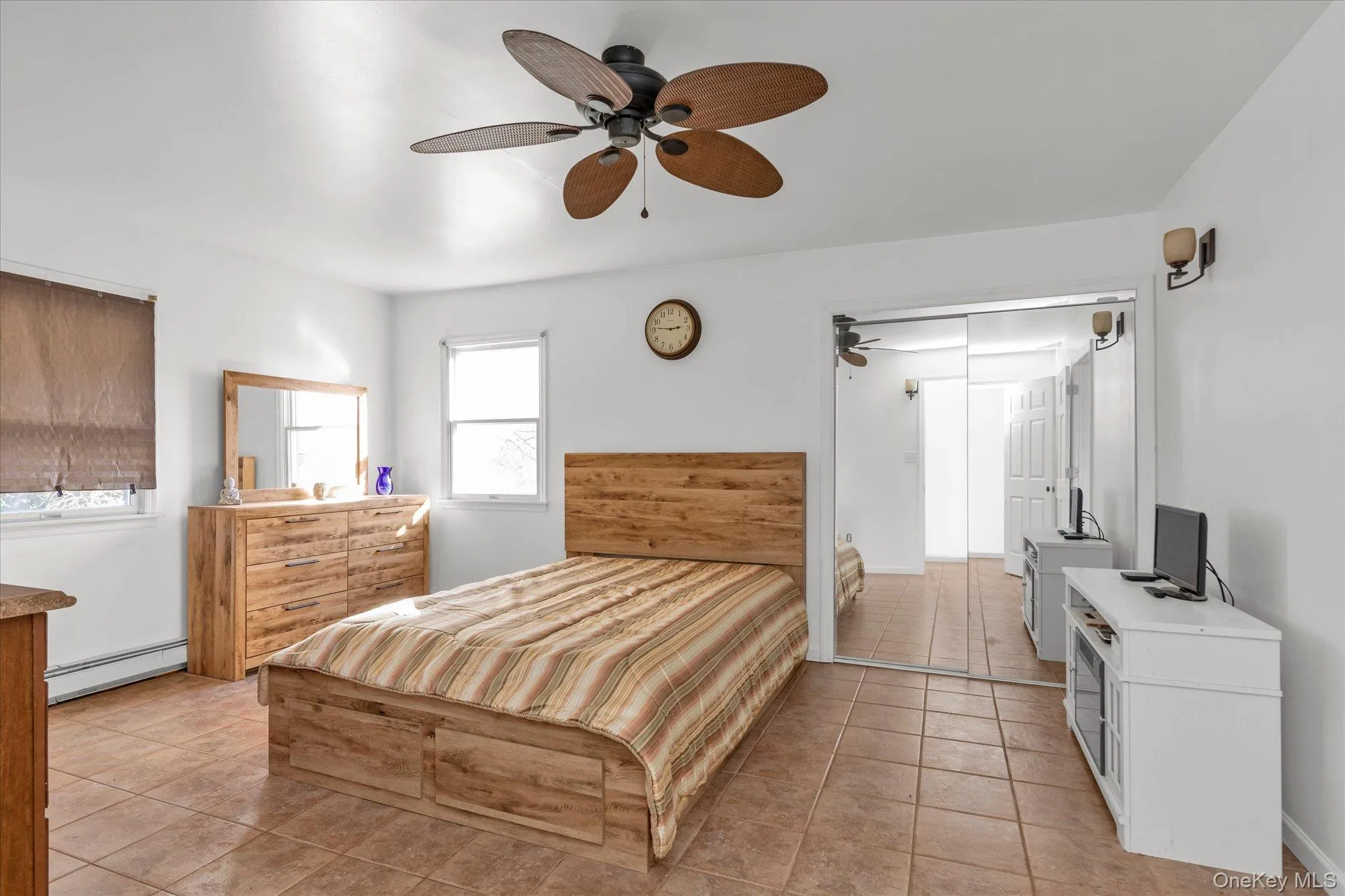 Bedroom featuring a baseboard radiator, ceiling fan, and light tile patterned flooring Bedroom featuring a baseboard radiator, ceiling fan, and light tile patterned flooring