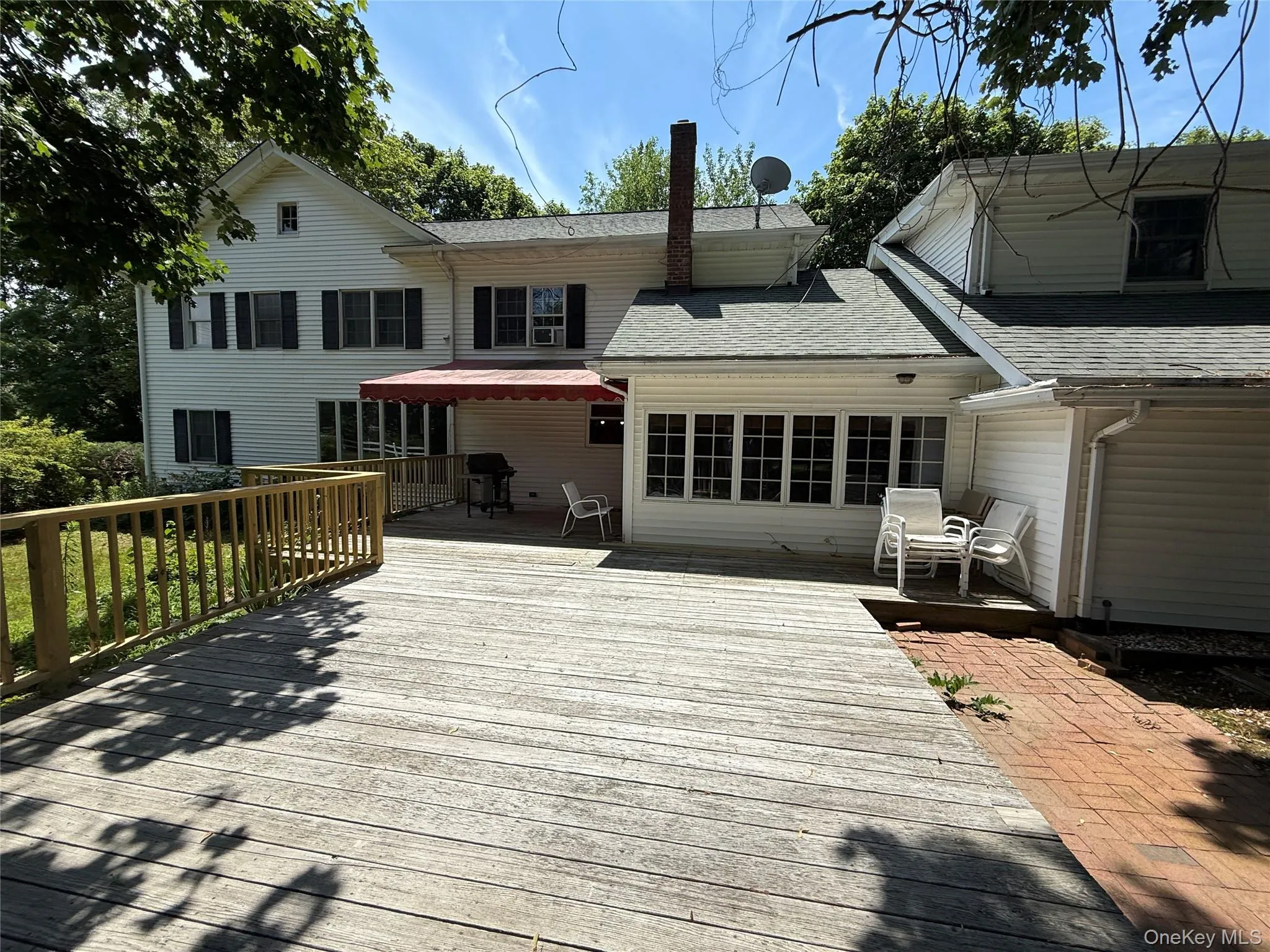 Back of property featuring roof with shingles, a deck, and a chimney Back of property featuring roof with shingles, a deck, and a chimney