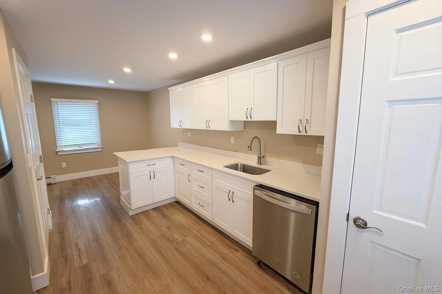 Kitchen featuring white cabinetry, appliances with stainless steel finishes, recessed lighting, light wood-type flooring, and a peninsula Kitchen featuring white cabinetry, appliances with stainless steel finishes, recessed lighting, light wood-type flooring, and a peninsula