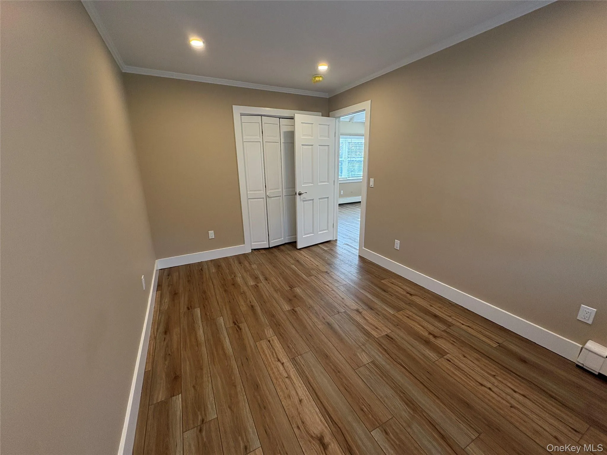 Unfurnished bedroom with wood finished floors, crown molding, a closet, and recessed lighting Unfurnished bedroom with wood finished floors, crown molding, a closet, and recessed lighting