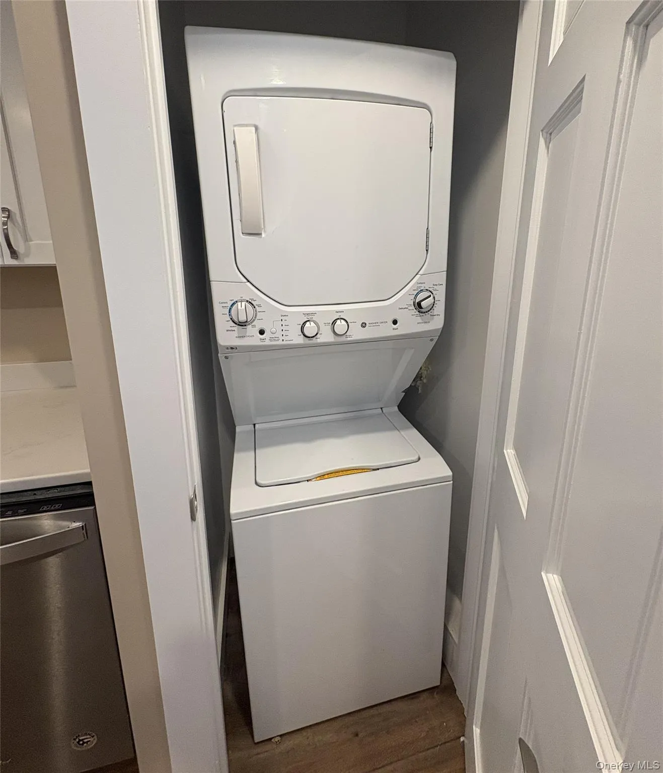 Washroom featuring dark wood-style flooring and stacked washer and clothes dryer Washroom featuring dark wood-style flooring and stacked washer and clothes dryer