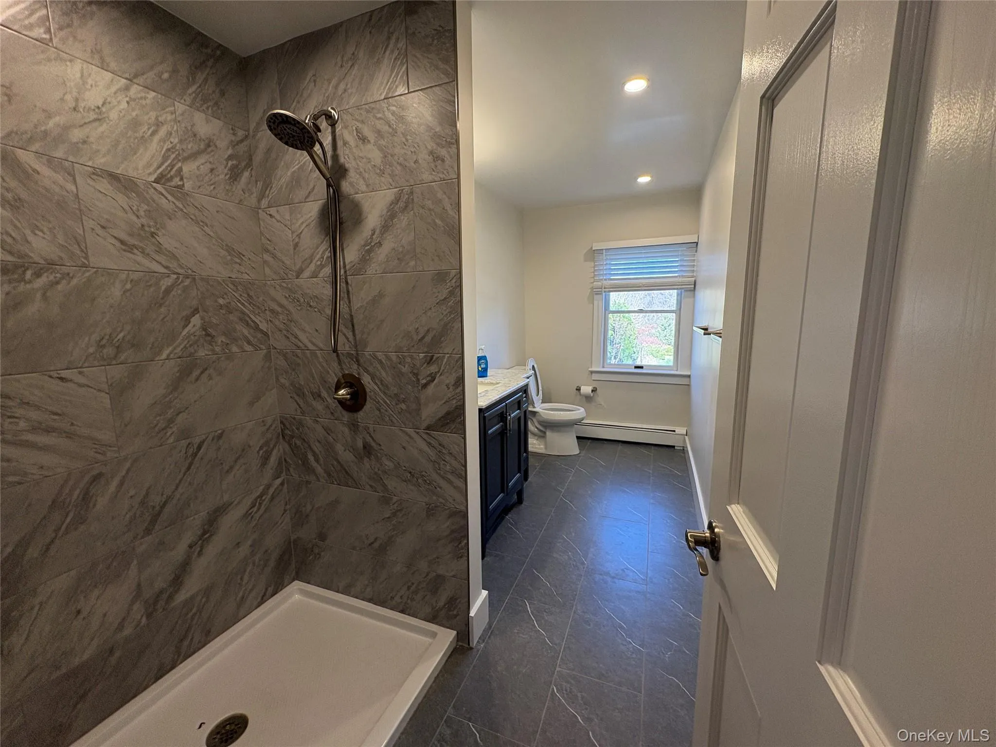 Full bathroom featuring a stall shower, vanity, baseboard heating, and recessed lighting Full bathroom featuring a stall shower, vanity, baseboard heating, and recessed lighting