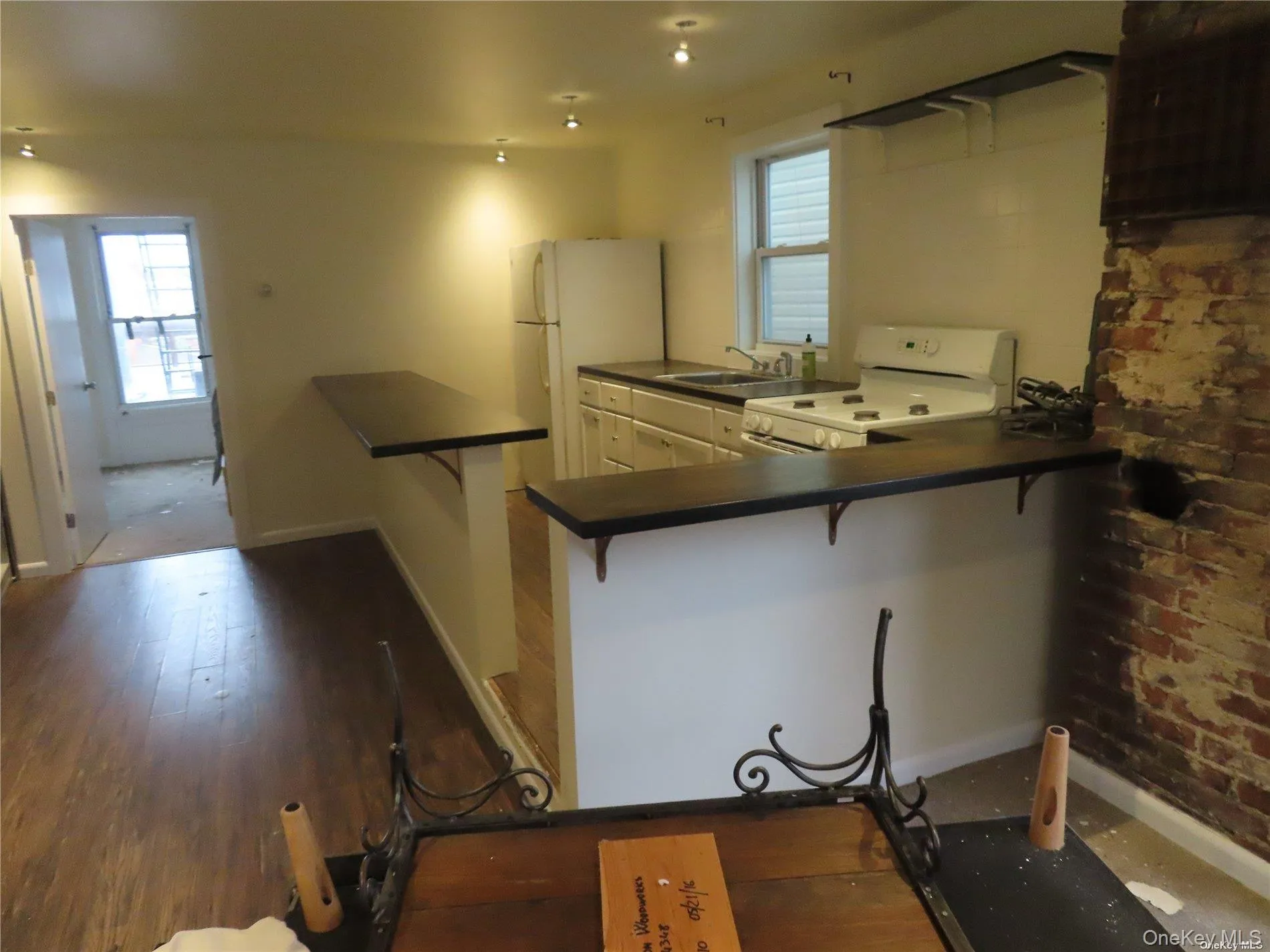Kitchen with dark countertops, a kitchen bar, white appliances, and a peninsula Kitchen with dark countertops, a kitchen bar, white appliances, and a peninsula
