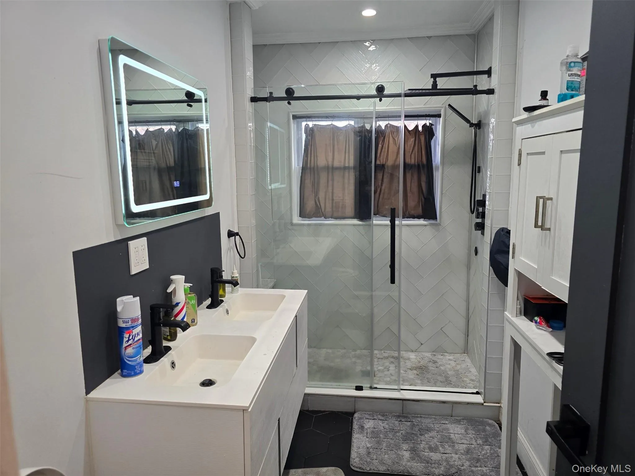 Full bath with double vanity, a stall shower, and dark tile patterned flooring Full bath with double vanity, a stall shower, and dark tile patterned flooring
