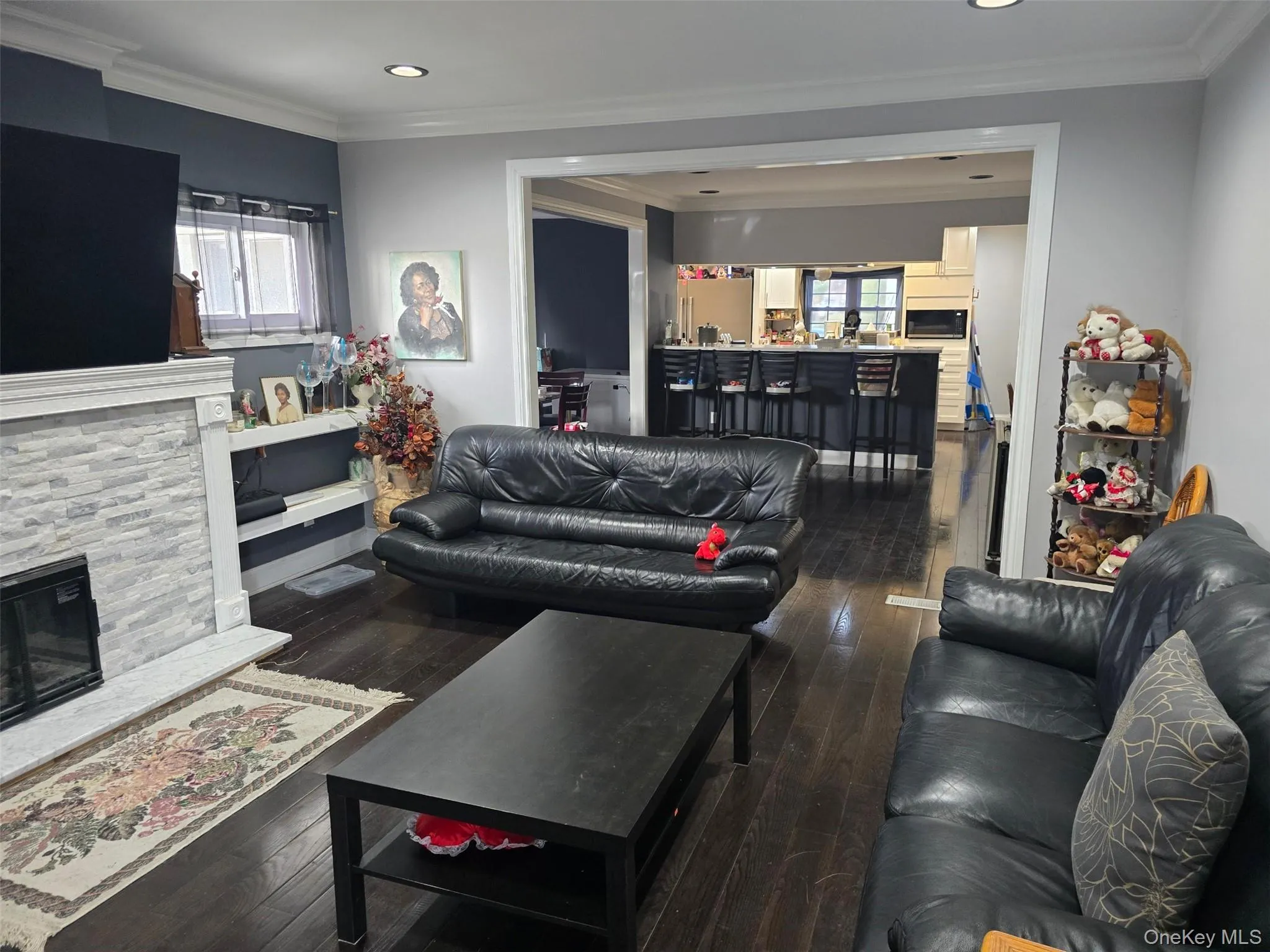 Living area with ornamental molding, dark wood-style floors, a fireplace, and recessed lighting Living area with ornamental molding, dark wood-style floors, a fireplace, and recessed lighting