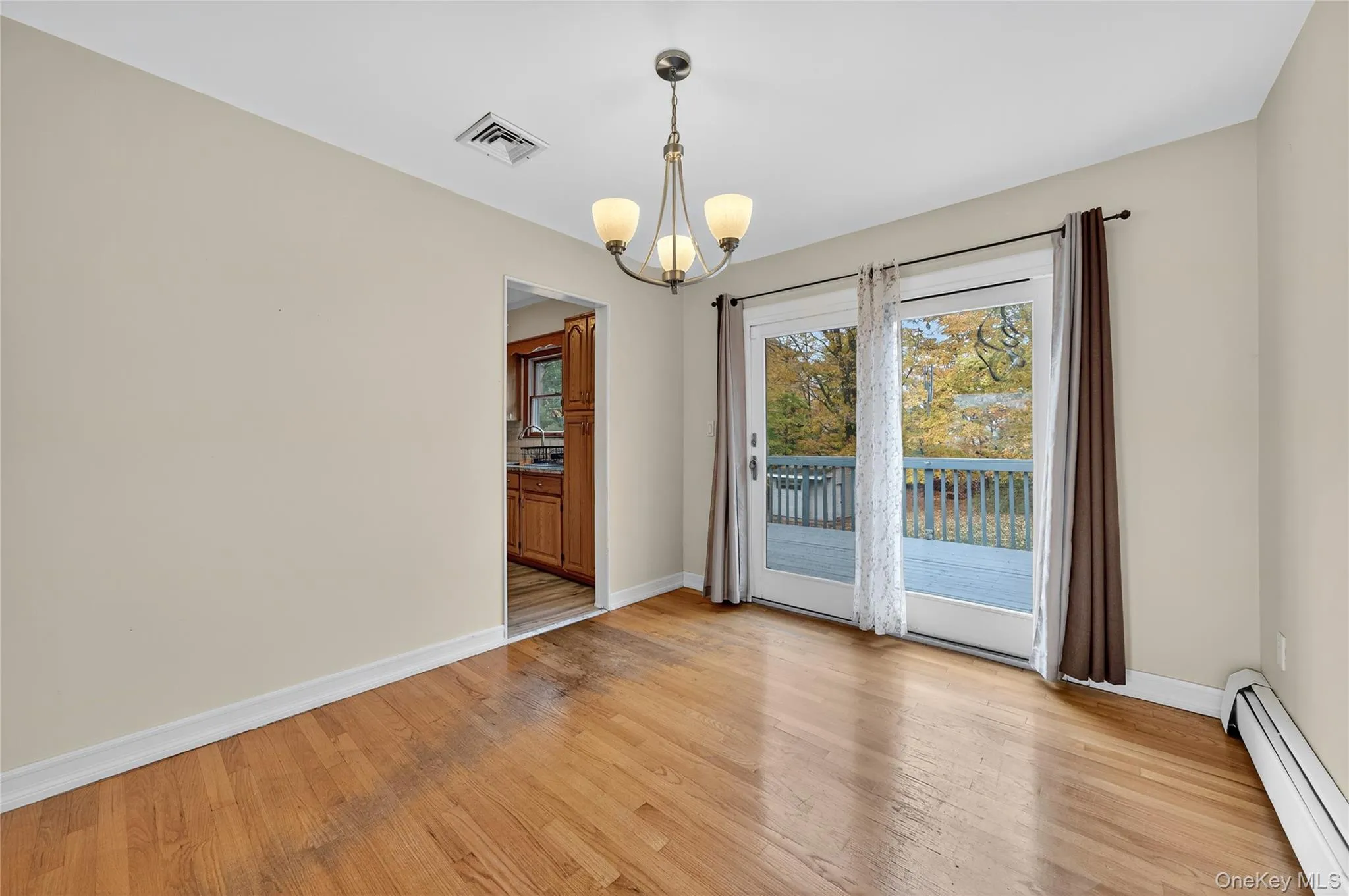 Spare room featuring baseboard heating, a chandelier, and light wood-style flooring Spare room featuring baseboard heating, a chandelier, and light wood-style flooring