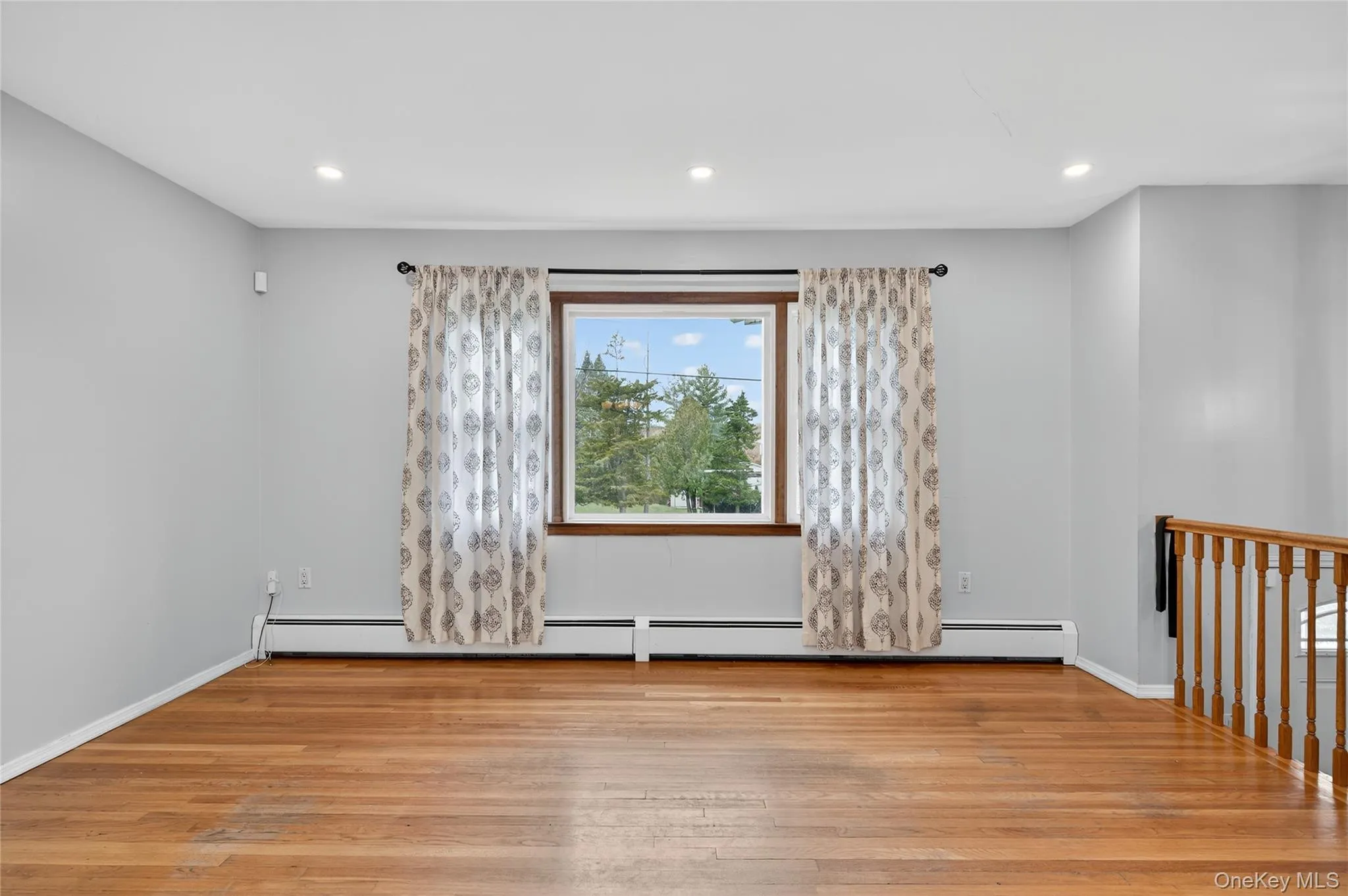 Empty room with light wood-style floors, recessed lighting, and a baseboard radiator Empty room with light wood-style floors, recessed lighting, and a baseboard radiator