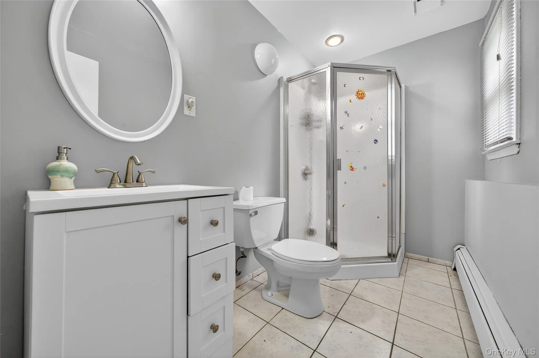Full bathroom with baseboard heating, light tile patterned floors, a stall shower, and vanity Full bathroom with baseboard heating, light tile patterned floors, a stall shower, and vanity