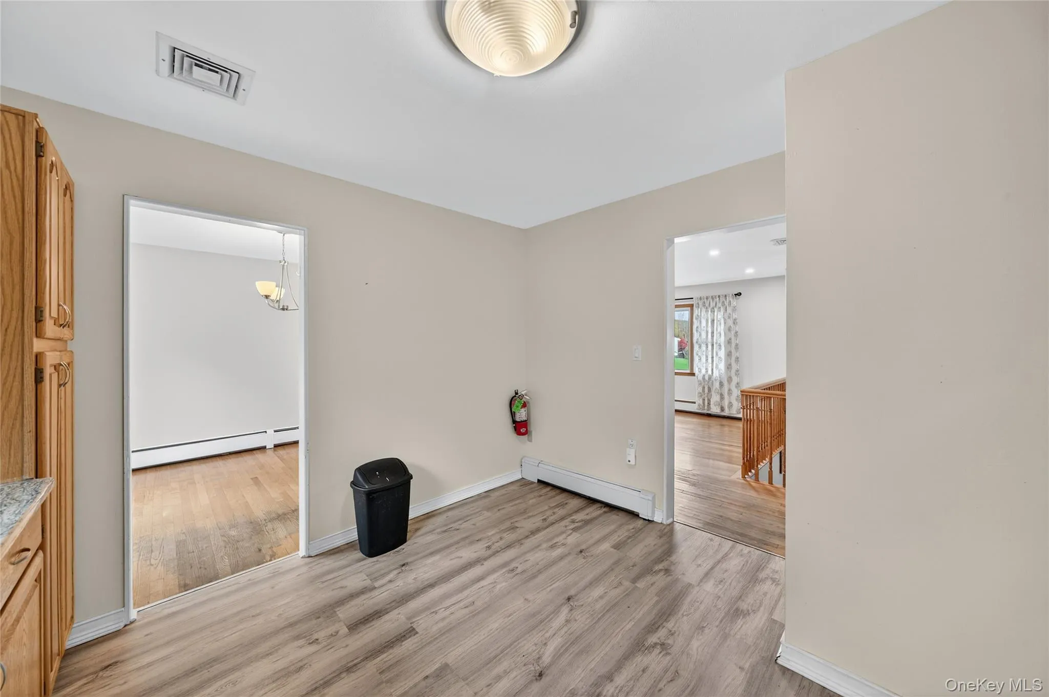 Empty room with light wood-style floors, a baseboard heating unit, and a chandelier Empty room with light wood-style floors, a baseboard heating unit, and a chandelier