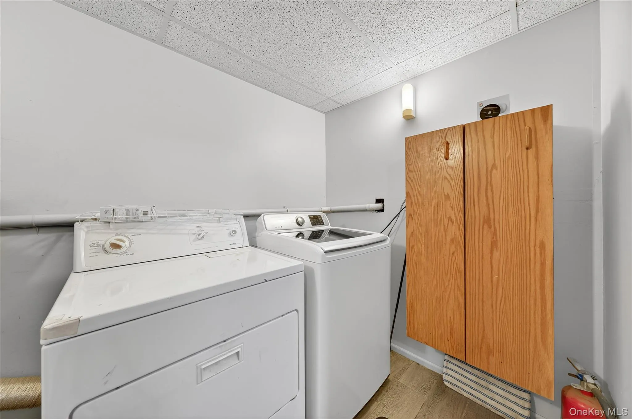 Washroom featuring a drop ceiling, light wood-type flooring, and washer and dryer Washroom featuring a drop ceiling, light wood-type flooring, and washer and dryer